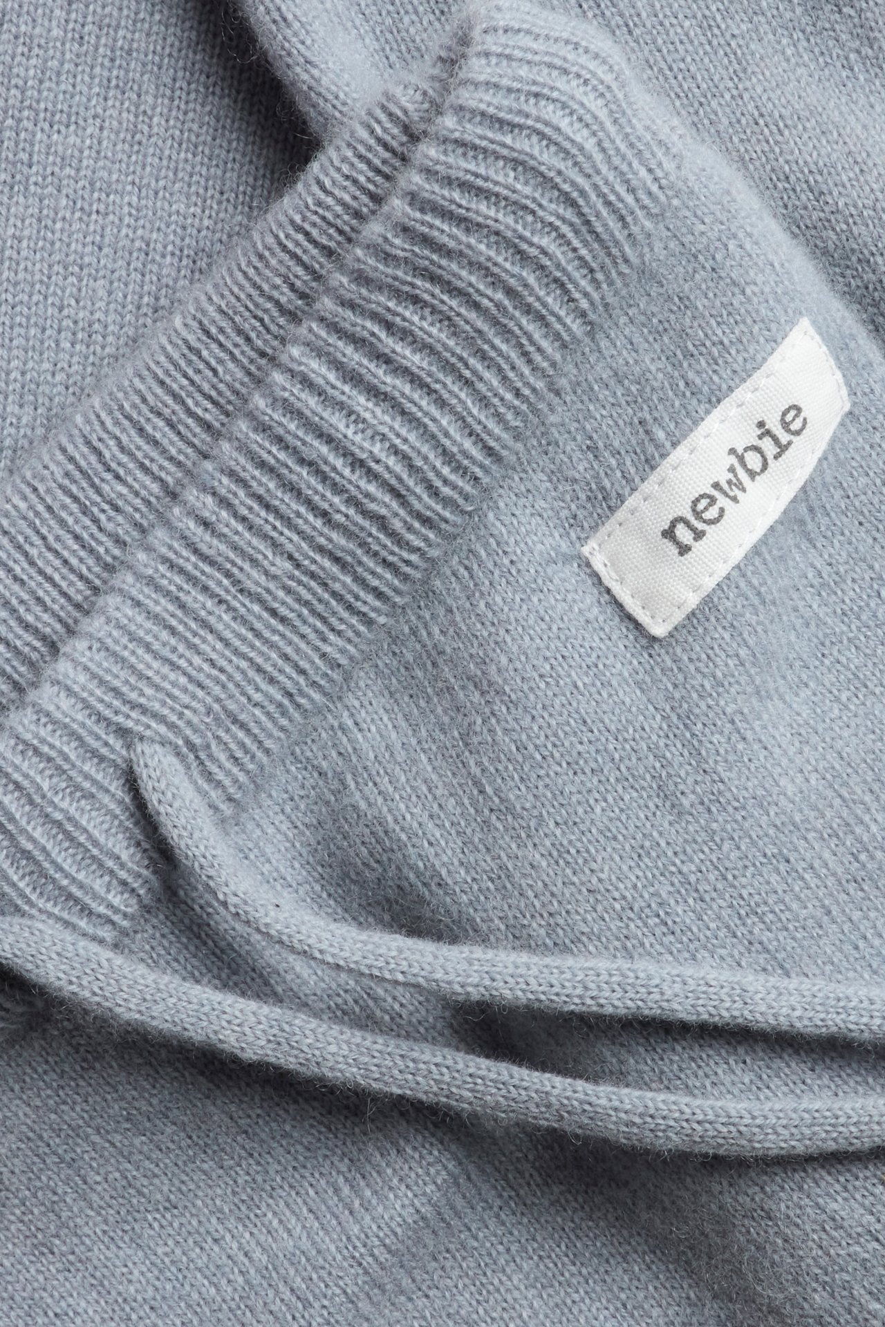 Close-up of light blue plain-knit wool-cashmere pants with ribbed waistband and drawstring.