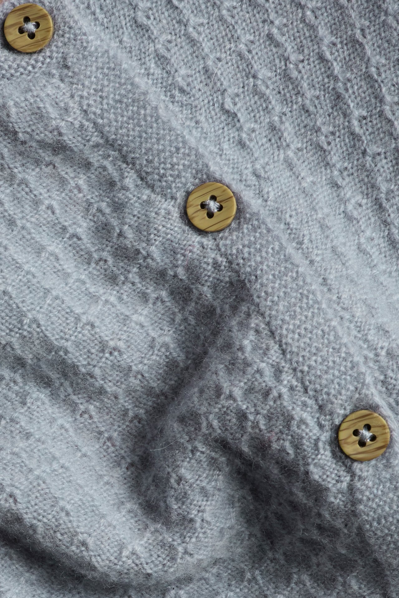 Close-up of a light blue structured knit wool and cashmere blend cardigan with wooden side buttons.