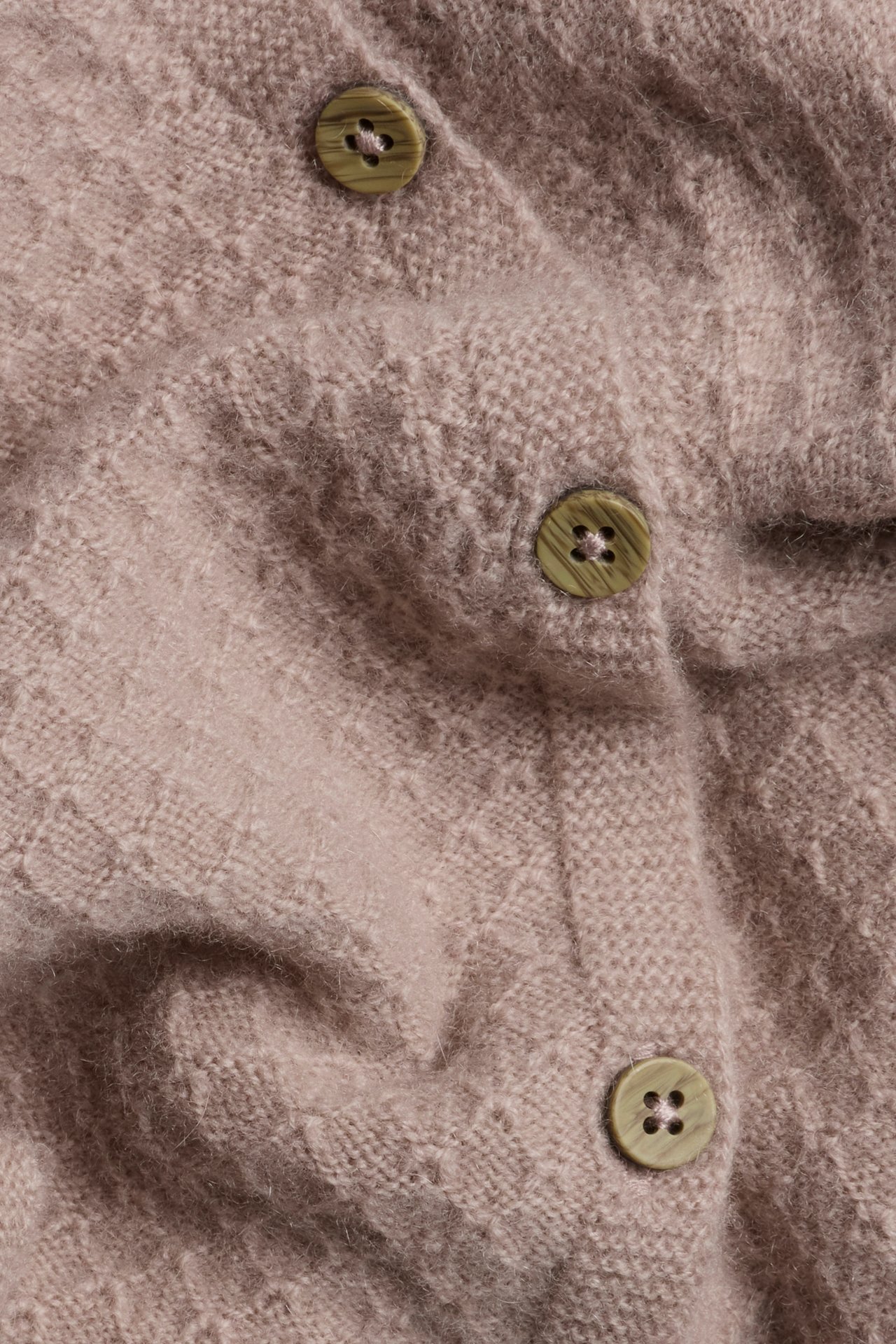 Close-up of a pink structured knit wool and cashmere blend cardigan with three light green buttons.