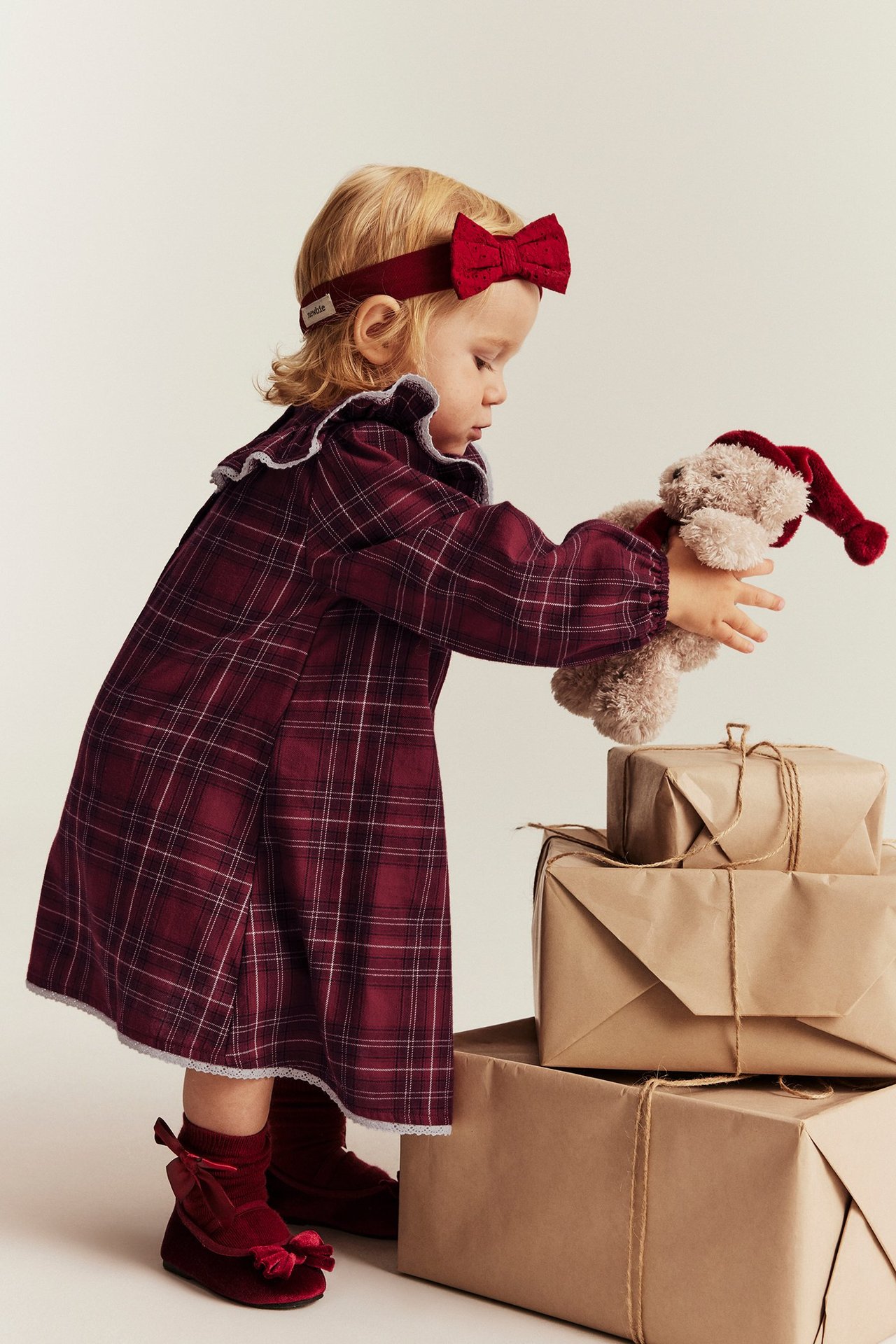 Mädchen in rotem karierten Weihnachtskleid mit Rüsche, Spitzenkanten, Knöpfen am Rücken.