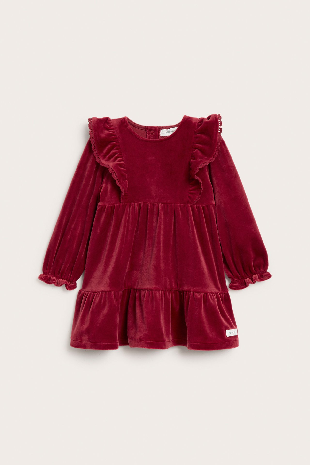 Front view of a kid's solid red velour dress with shoulder ruffles, long sleeves, and ruffled hem.