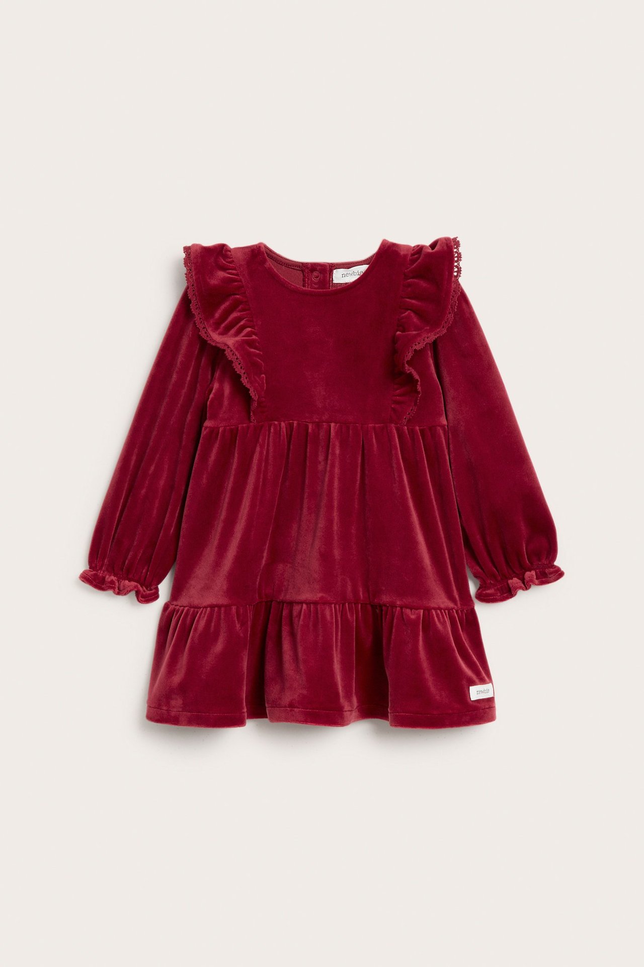 Front view of a kid's solid red velour dress with shoulder ruffles, long sleeves, and ruffled hem.