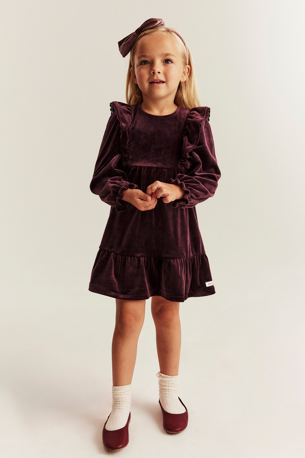 Young girl in lilac velour dress with ruffles, back buttons, long sleeves, and round neck.