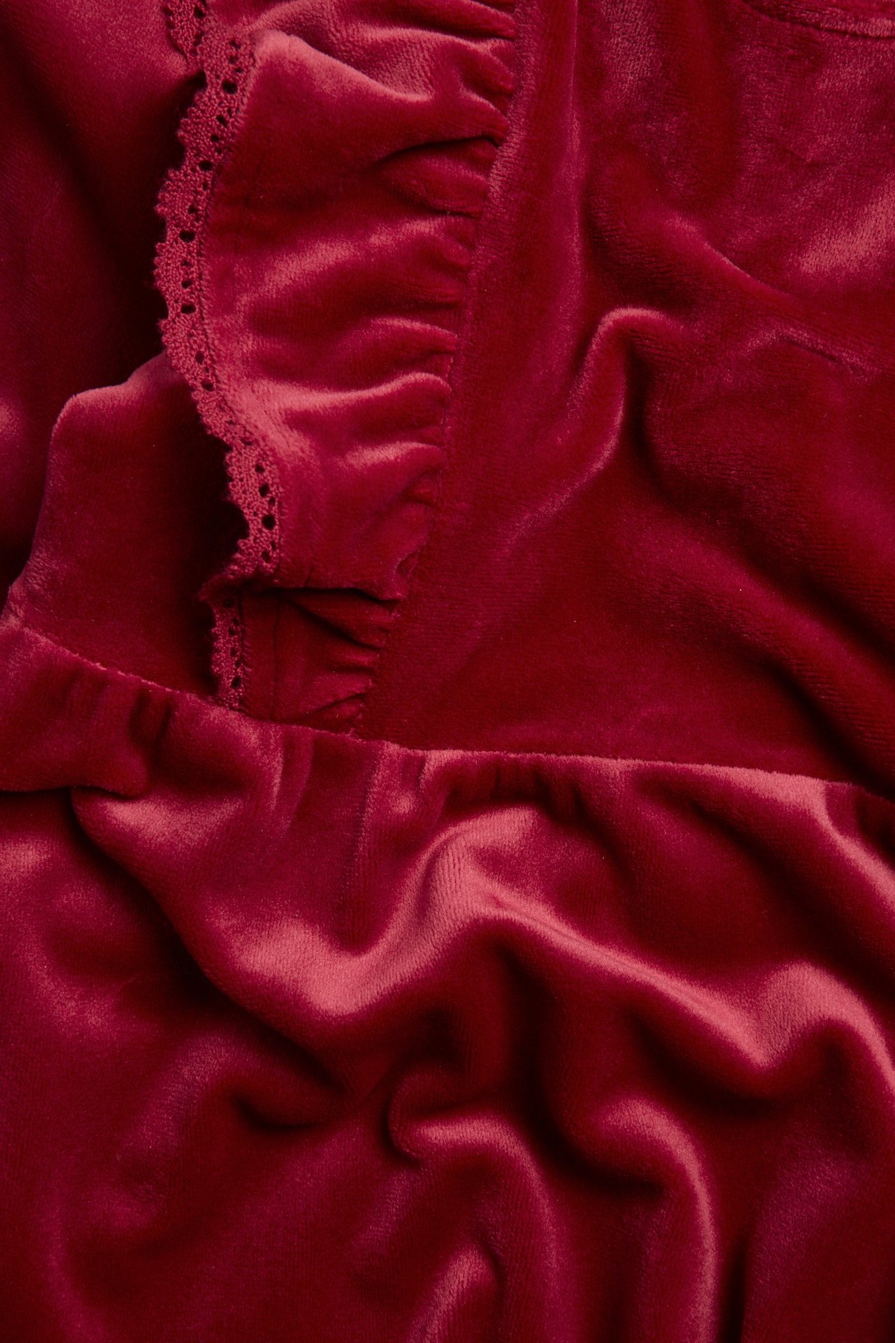Close-up of a red velour dress with ruffles and lace trim.