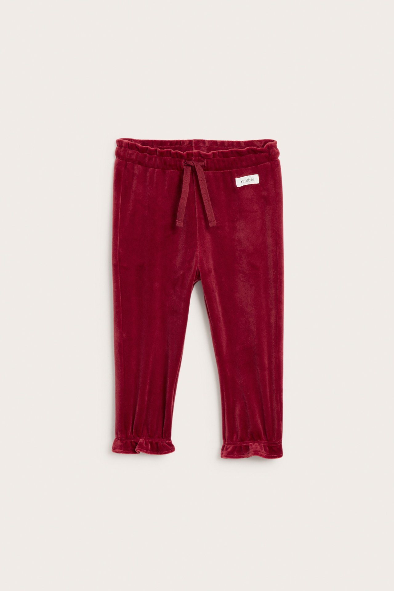Front view of dark red velvet baby pants with an elastic waist and ruffled ankles.