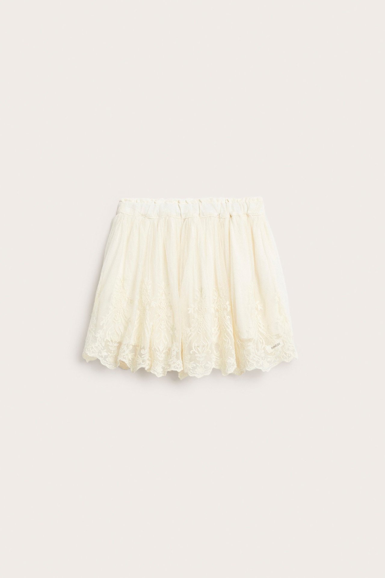 Front view of a light beige embroidered mesh skirt with an elastic waist and lining.