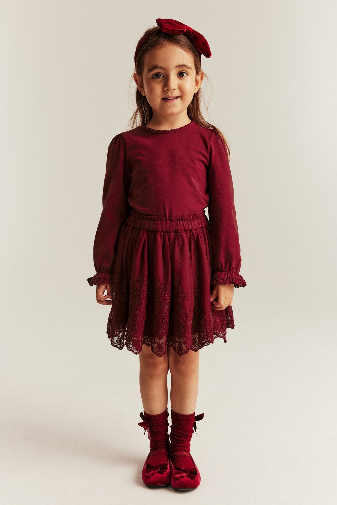 Girl in embroidered mesh skirt, lined, adjustable waist, long sleeves.