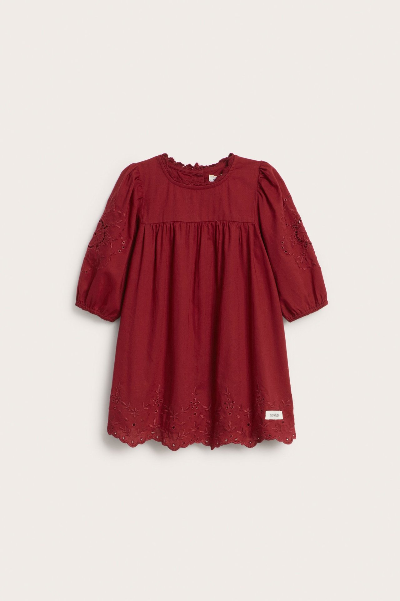 Front view: red kid's cotton dress with embroidered 3/4 puff sleeves, lace trim, and eyelet hem.