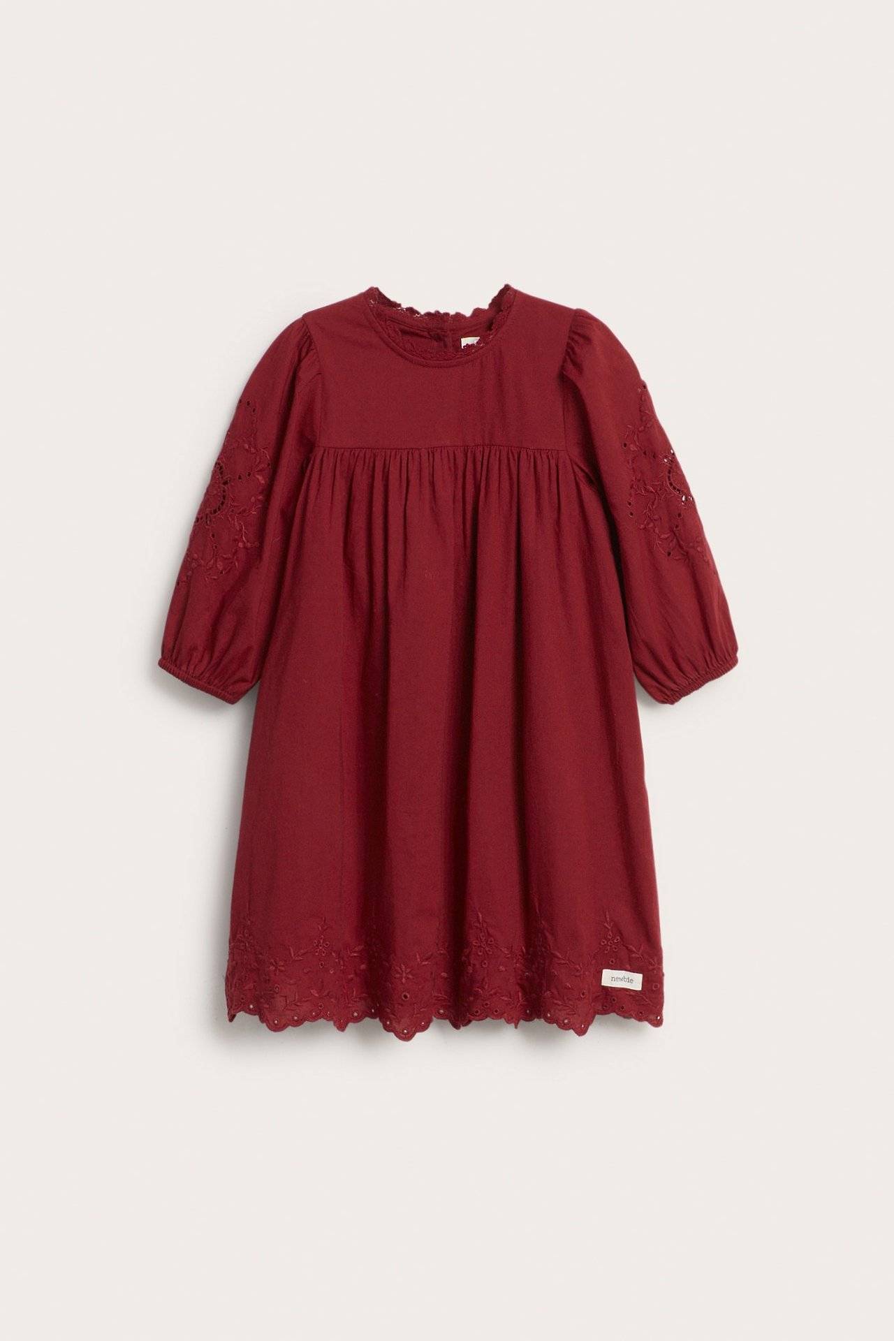 Front view of a kid's red woven cotton dress with embroidered 3/4 puff sleeves and eyelet hem.