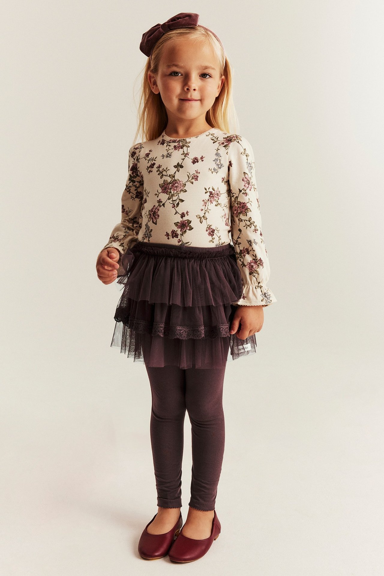 Lilac leggings with attached tulle skirt in three ruffles, adjustable waist, on girl.
