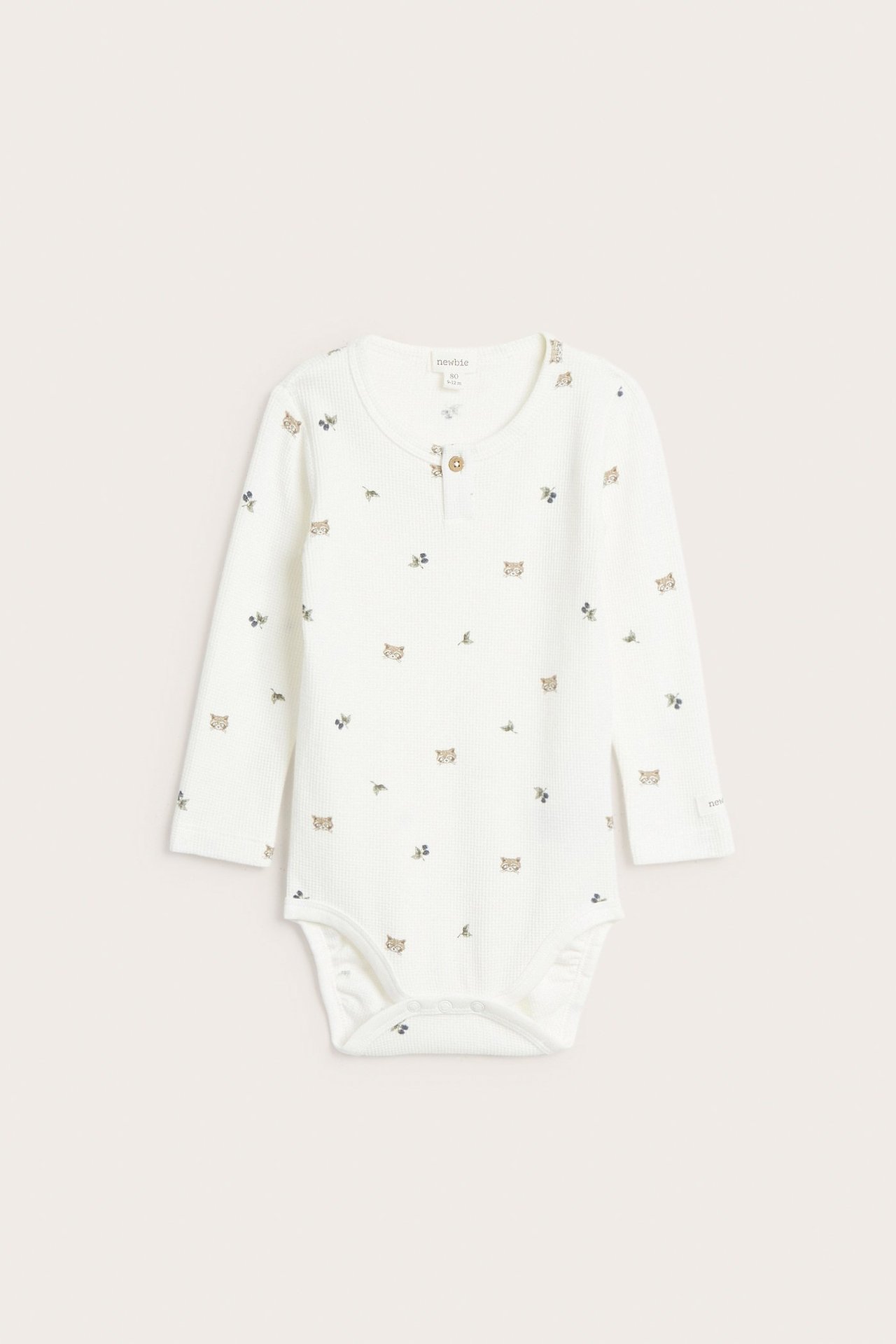 Vorderansicht: Off-white Waffelstrick Babybody mit Waschbär- und Blattmuster, Knopfleiste, Druckknöpfen.