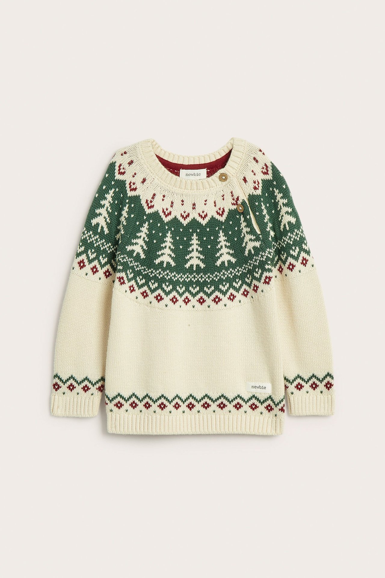 Front view of a kid's offwhite knitted cotton Christmas sweater with green fir trees, red jacquard pattern, and shoulder buttons.
