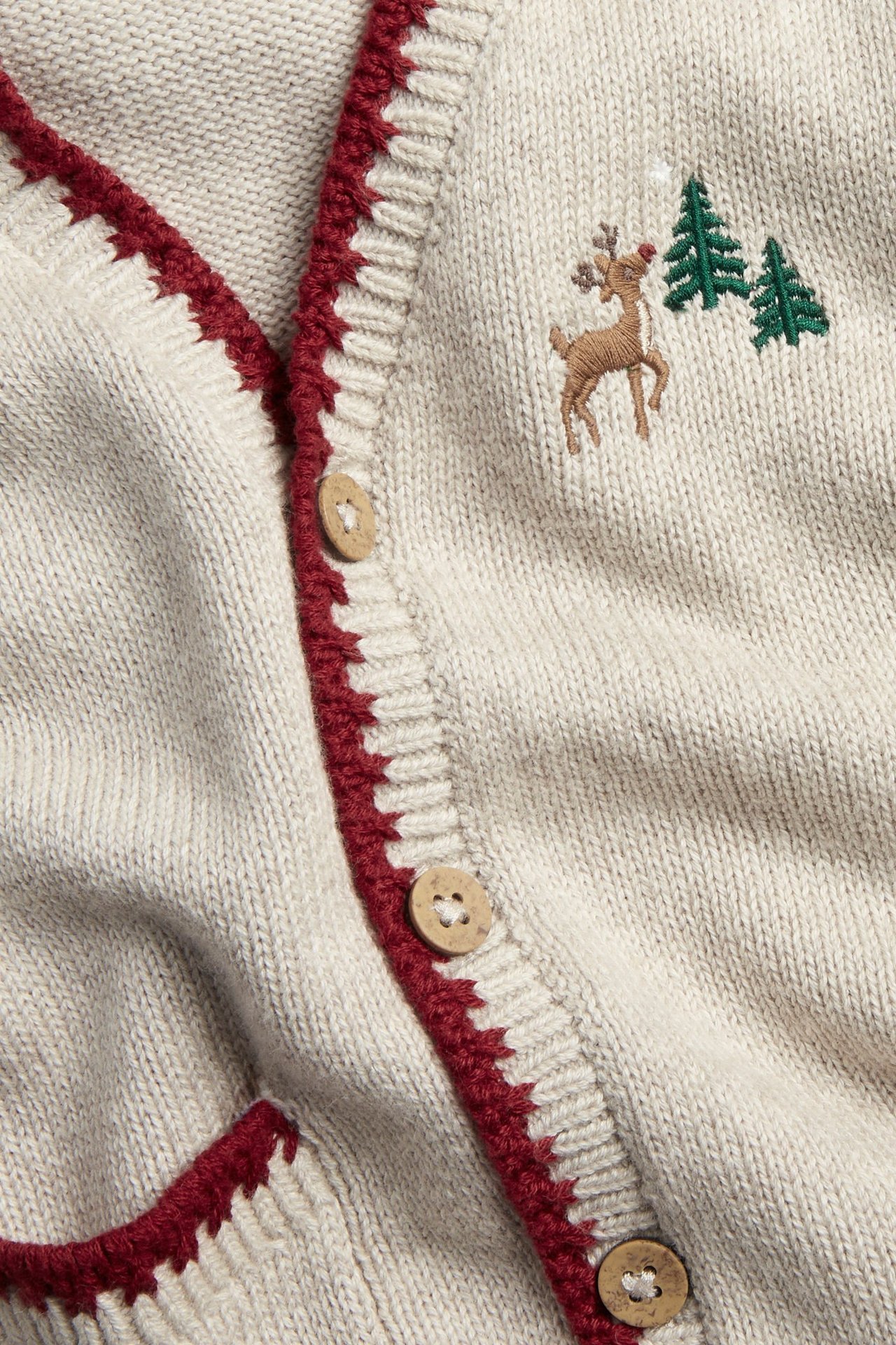 Close-up front view of a beige melange knitted Christmas vest with red trim, embroidered reindeer, and wooden buttons.