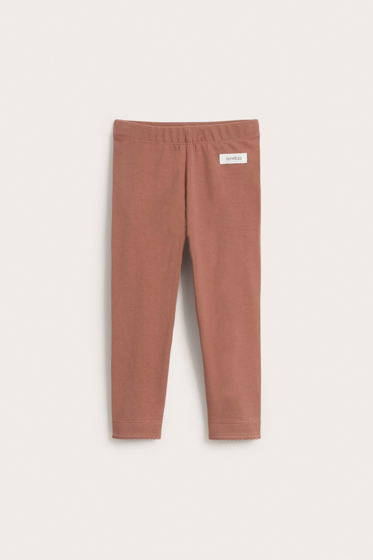 Front view of pink kid's leggings with elastic waist and scalloped lace trim at the ankles.