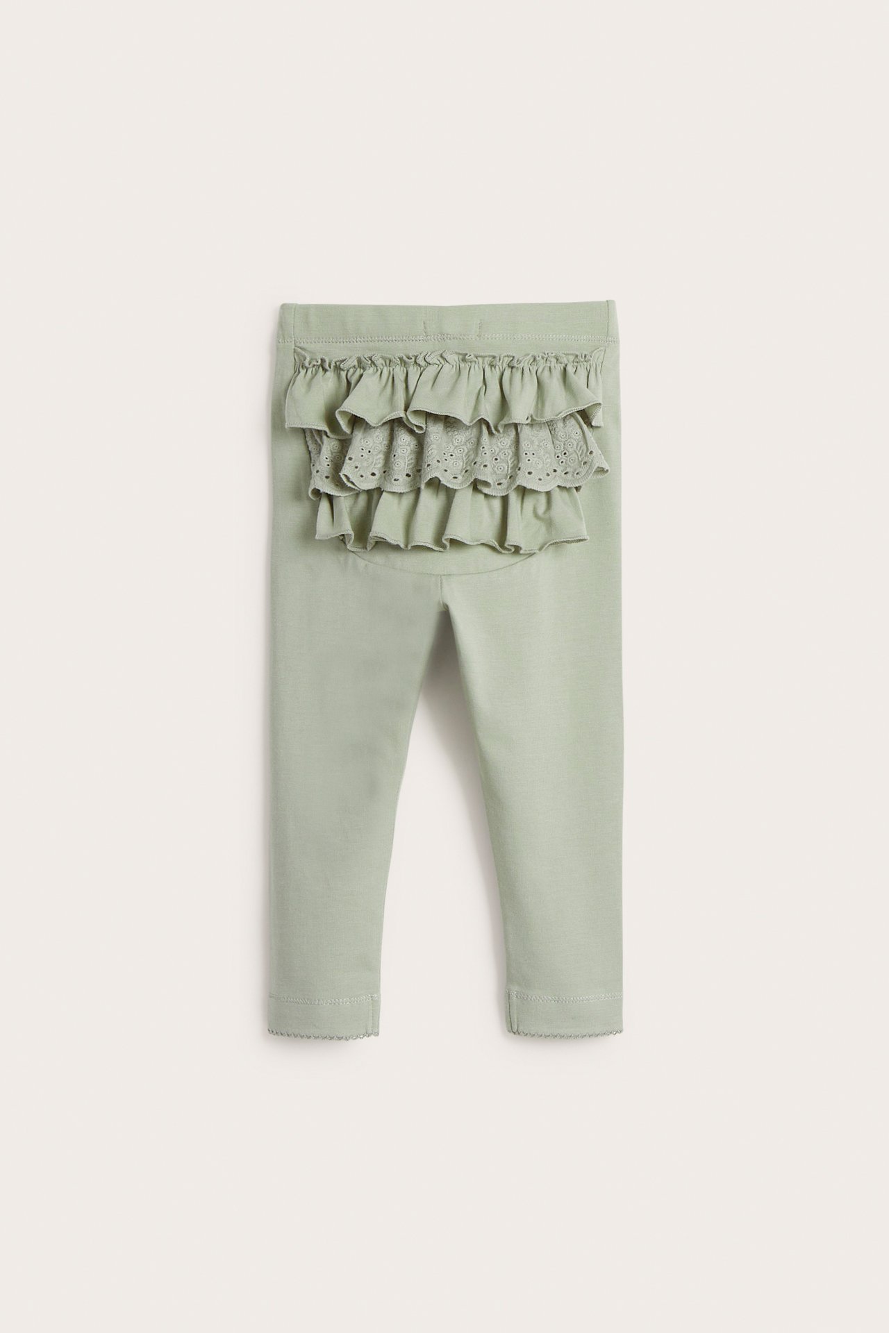 Rückansicht: Grüne Baby-Leggings mit Gummizug in der Taille, Rüschen und Spitzendetails hinten.