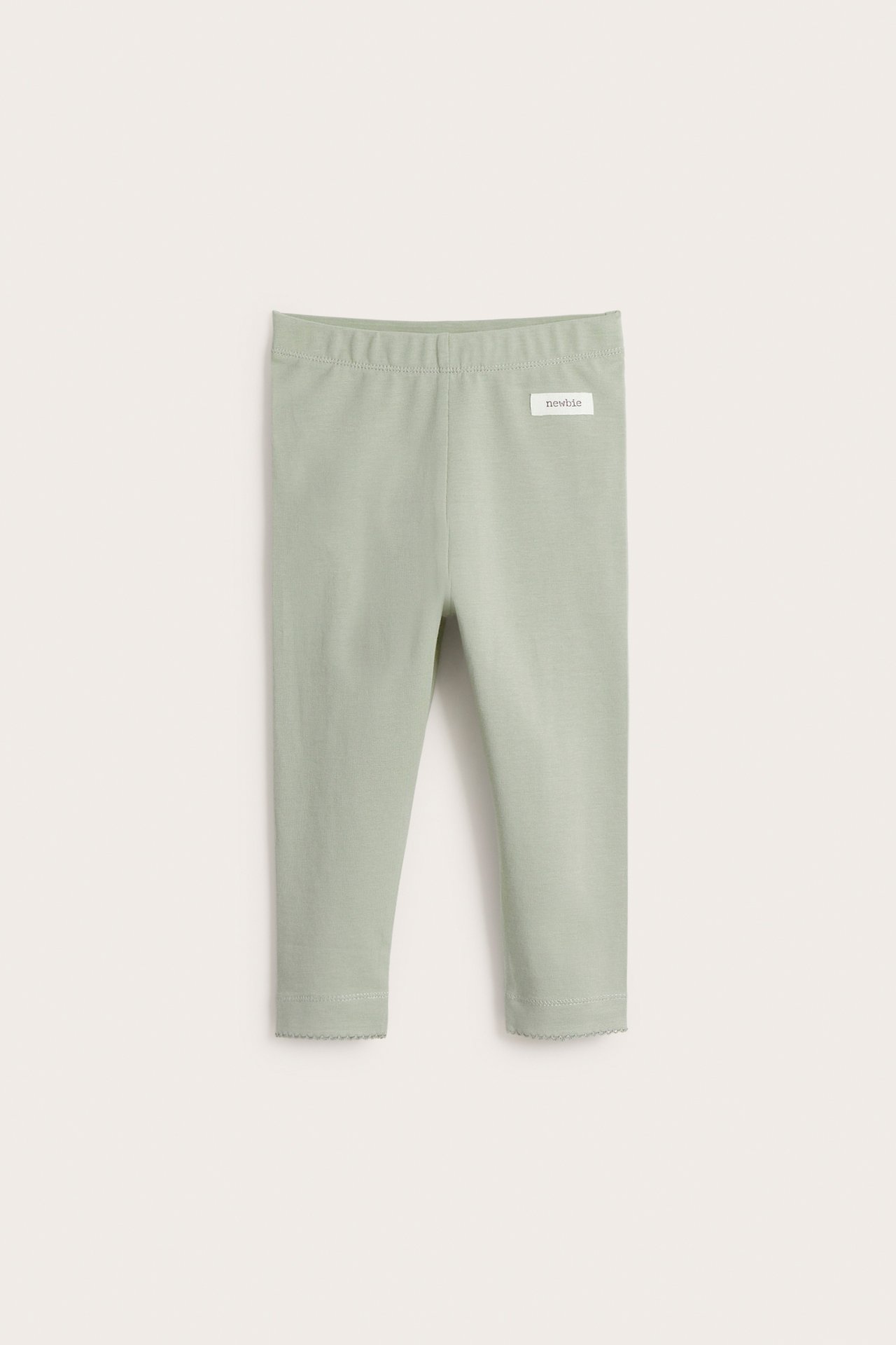 Vorderansicht hellgrüner Baby-Leggings aus Baumwolle mit Gummibund und gewellten Spitzenbündchen.