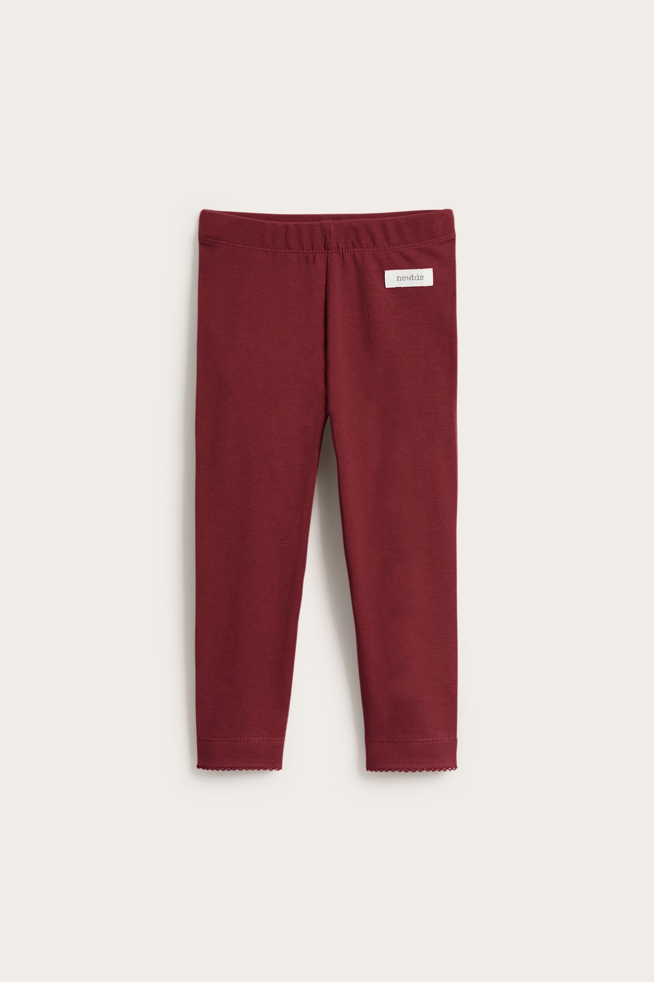 Front view of dark red kid's leggings with elastic waist and scalloped ankle trim.