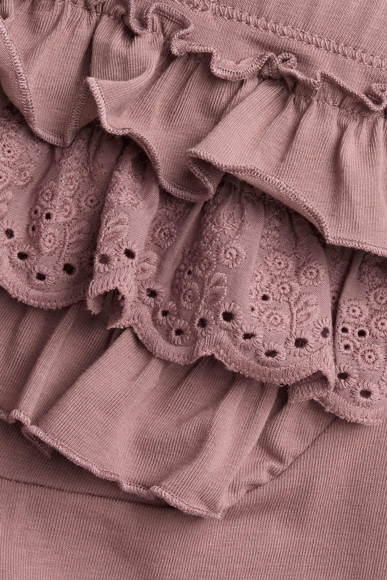 Close-up back view of dark pink leggings with ruffled layers and lace pattern.