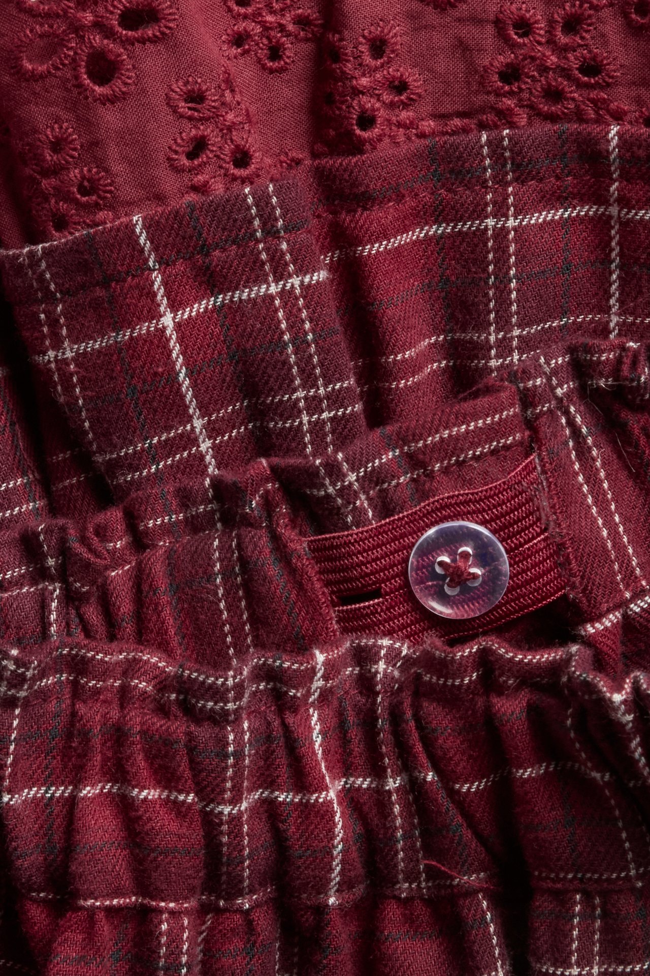 Close-up of a kid's red plaid skirt with ruffles, lace detail, and an adjustable elastic waistband.