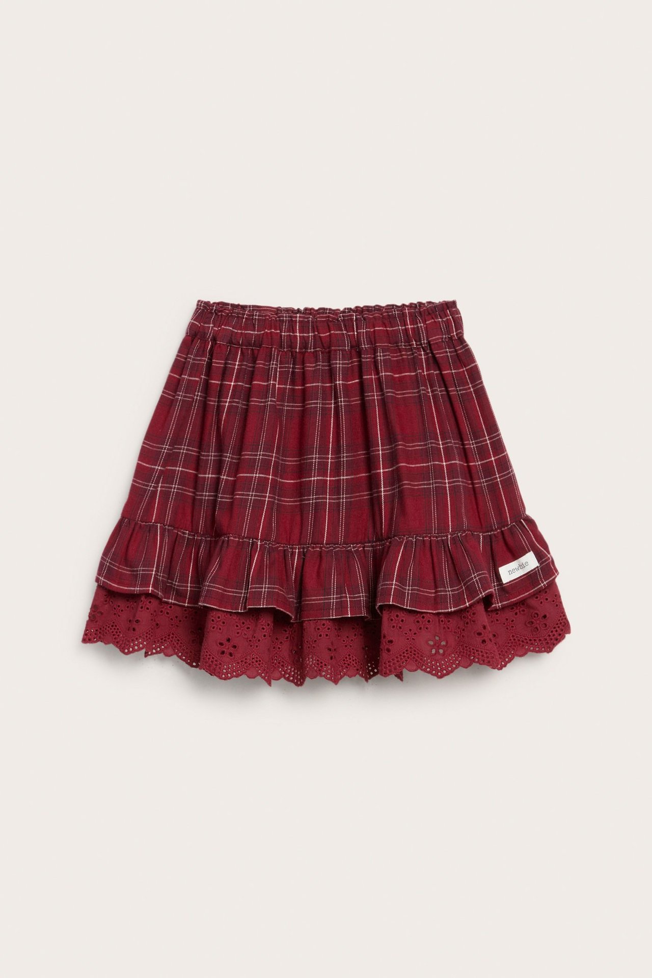 Front view of a kid's red plaid cotton skirt with elastic waist, ruffles, and broderie anglaise trim.