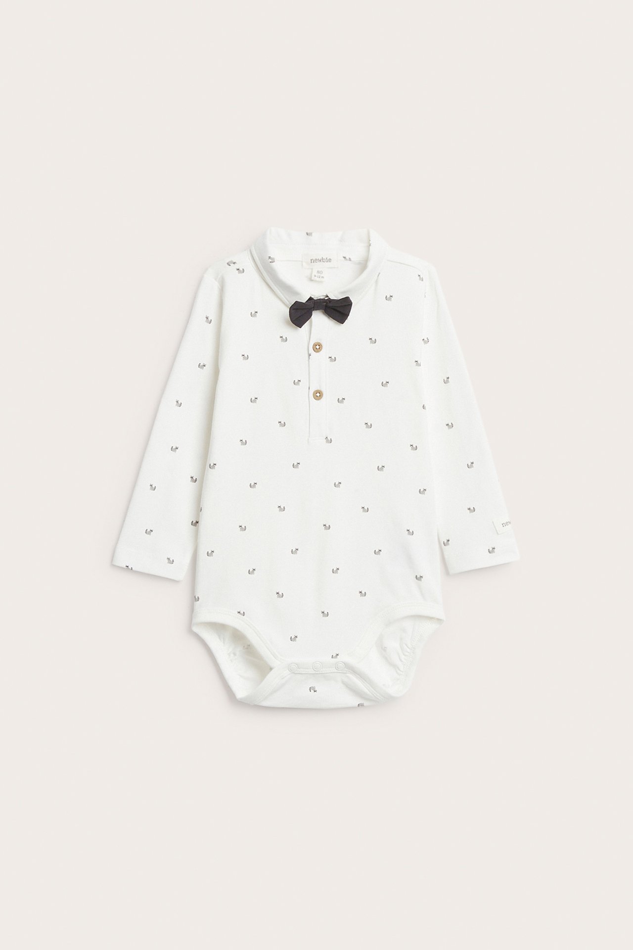 Front view: Off-white baby long-sleeved bodysuit with animal pattern, collar, front buttons, and black bow tie.