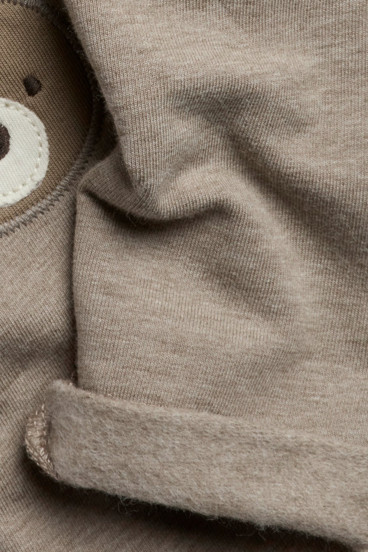 Close-up: Brown melange cotton leggings with brushed inside, rolled cuff, and bear knee application.