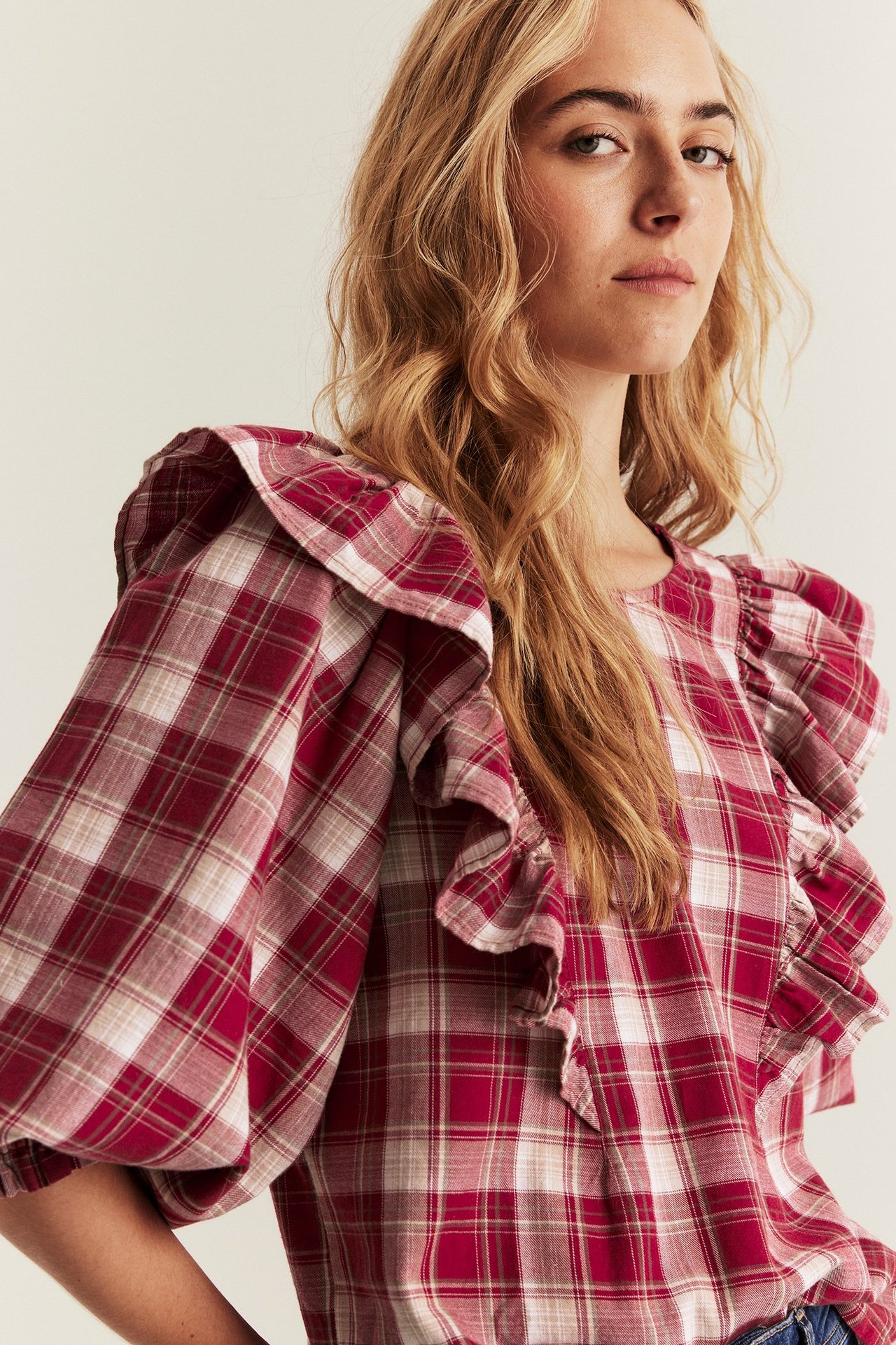 Red plaid woven blouse with ruffles on shoulders, front and back, and puff sleeves.