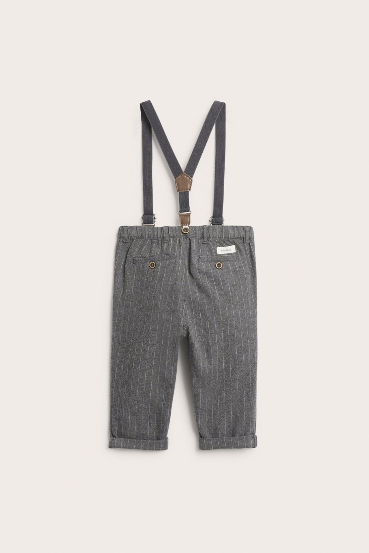 Front view of kid's grey pinstripe cotton trousers with adjustable dark grey suspenders and faux leather details.