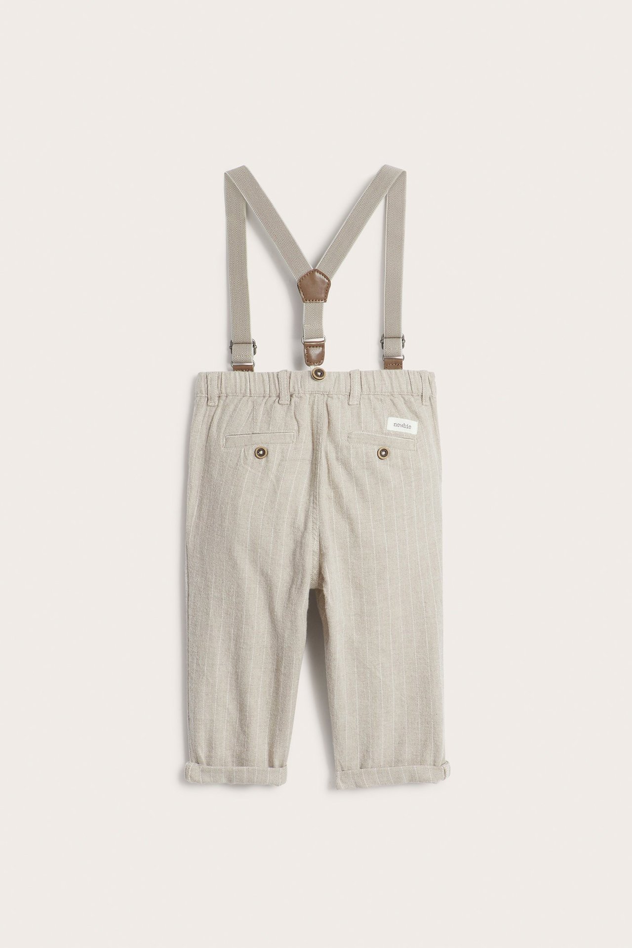 Rear view of kid's beige melange pinstriped woven trousers with adjustable khaki suspenders featuring brown faux leather.