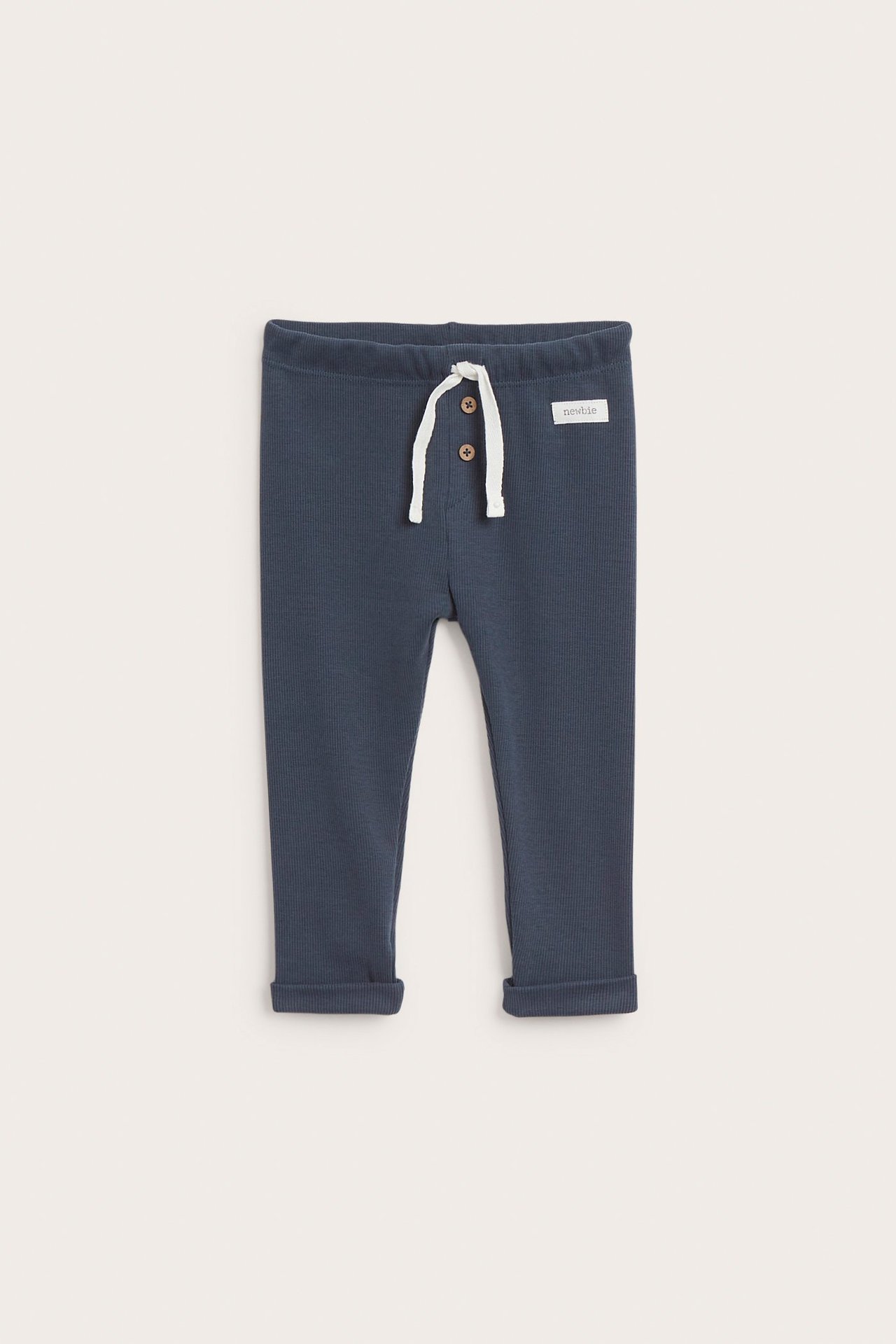Front view of dark blue ribbed baby leggings with elastic waist, white drawstring, two buttons, and rolled cuffs.
