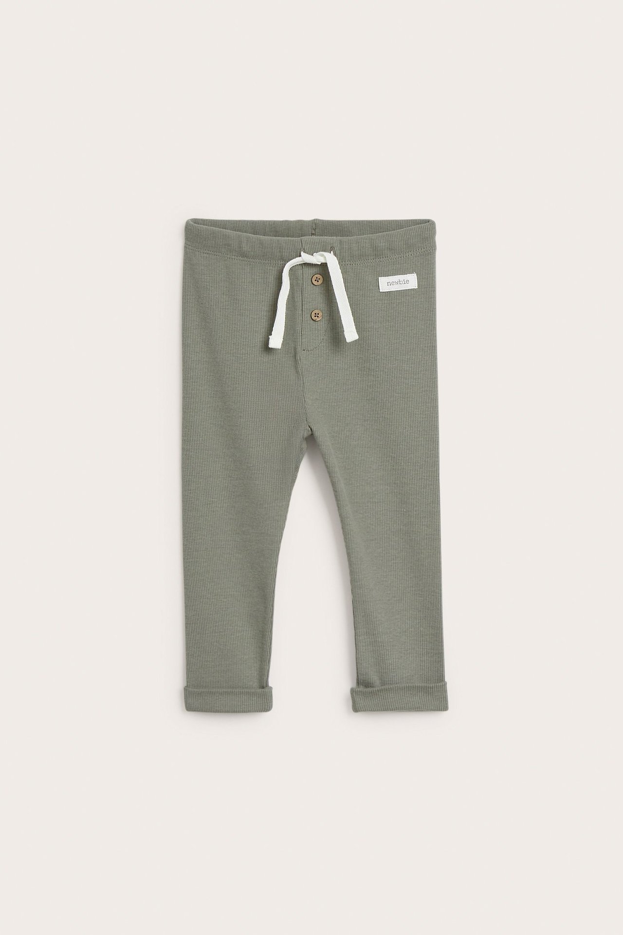 Front view of dark green ribbed baby leggings with white drawstring, two decorative buttons, and rolled cuffs.