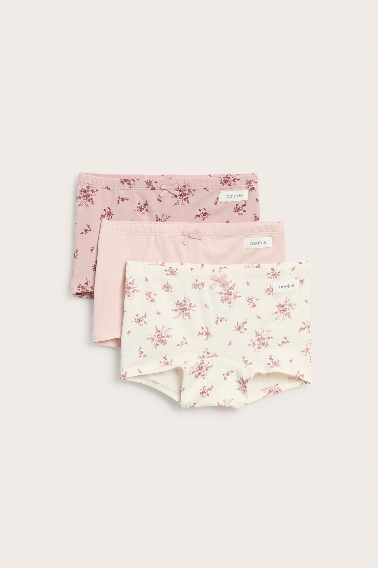 Vorderansicht von drei Kinder-Boxershorts aus Baumwolle: rosa und geblümt, jede mit einer kleinen Schleife.