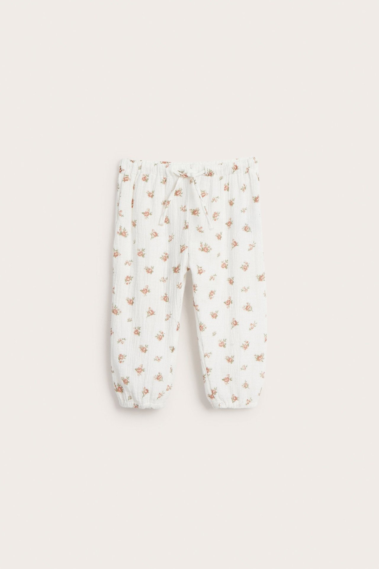 Vorderansicht: Off-white gewebte Babyhose aus Baumwolle mit Blumenmuster, Gummizug und Kordelzug.
