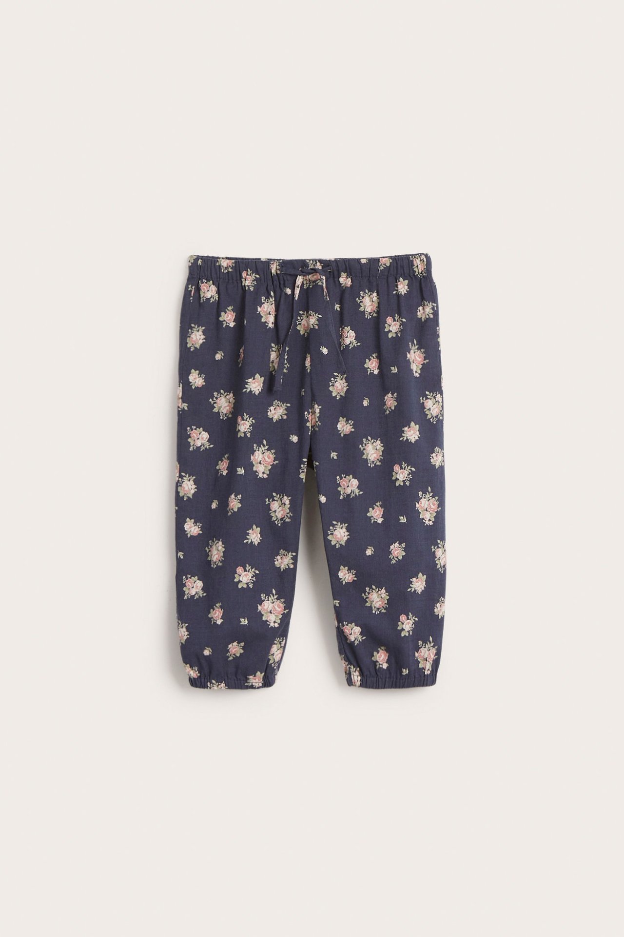 Front view of dark blue woven kid's puff pants with a pink floral pattern, elastic waist, and drawstring.