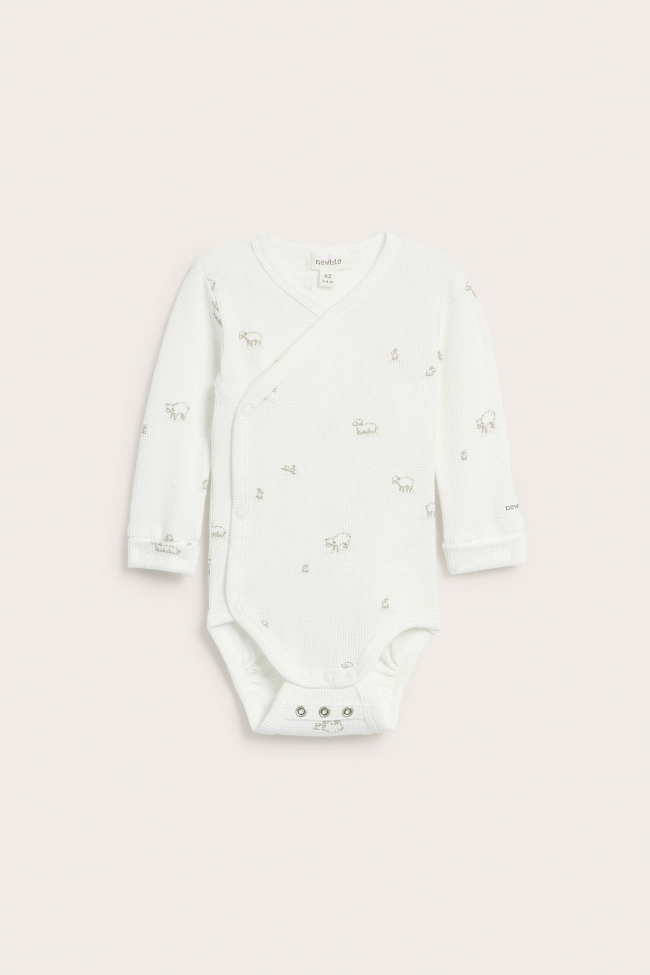 Vorderansicht eines cremefarbenen Baby-Langarm-Wickelbodys aus Waffelstrick mit Lamm-Print und Druckknöpfen.