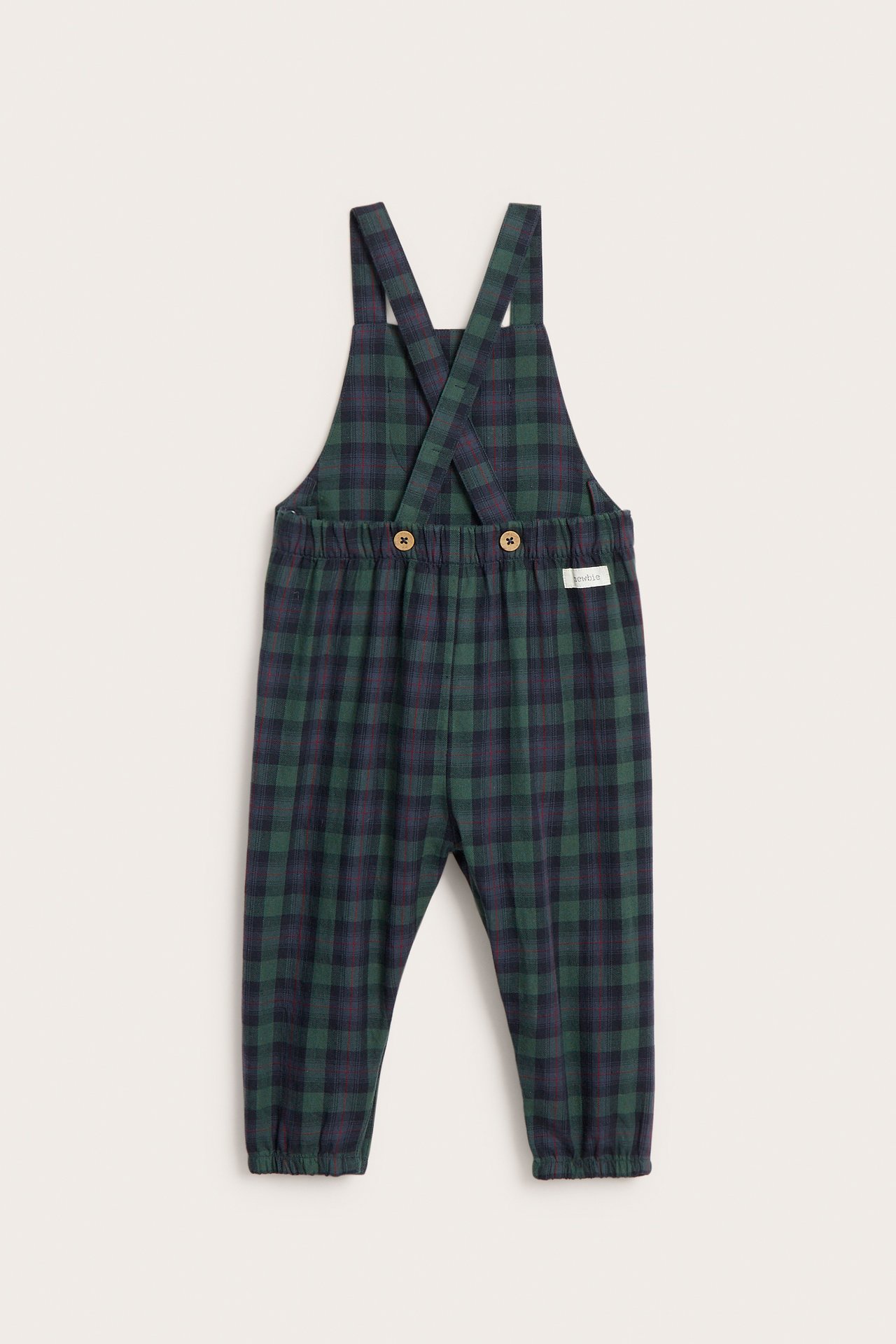 Back view of blue and green plaid cotton baby dungarees with criss-cross straps and wooden buttons.