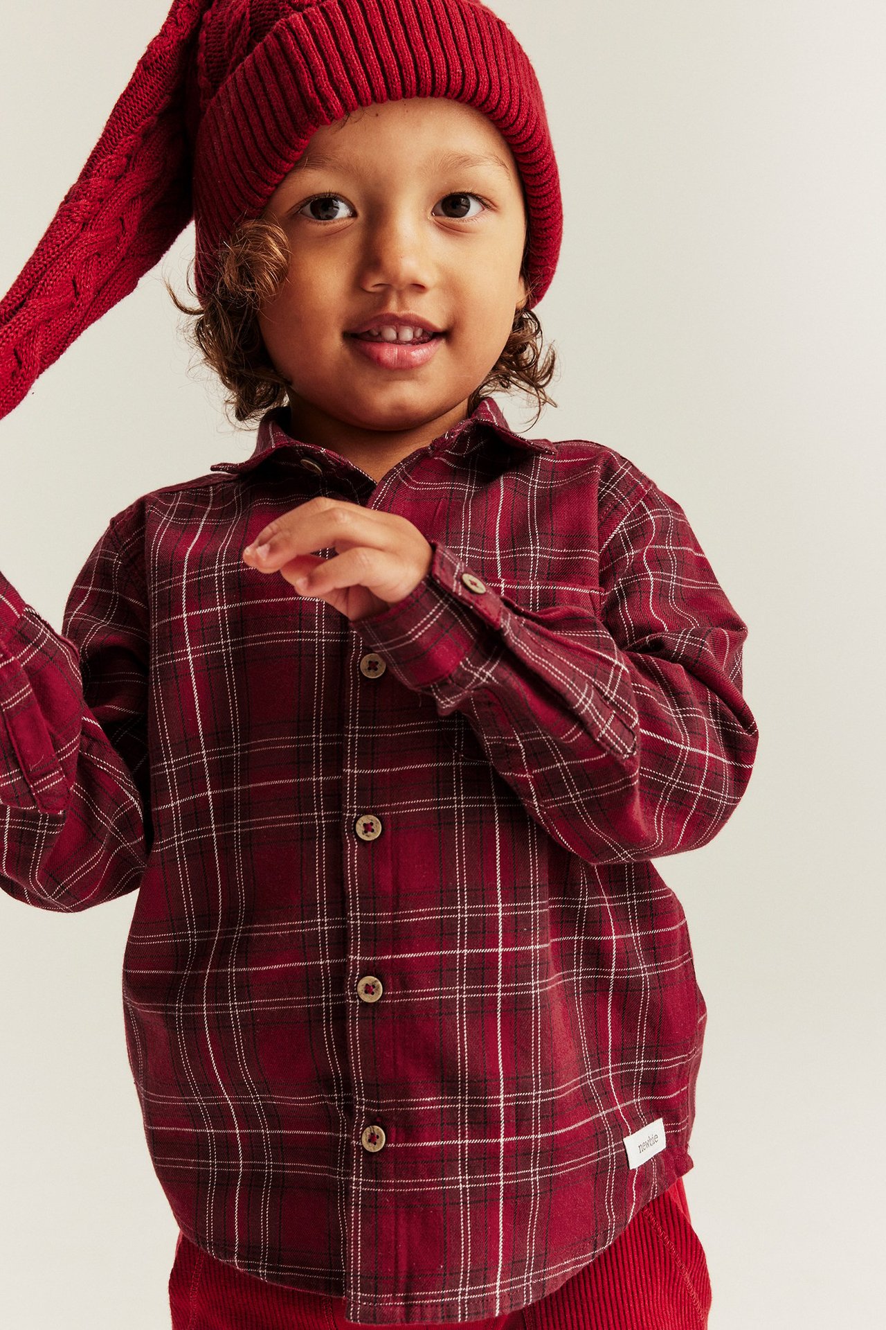 Mädchen in rotem kariertem Weihnachtsshirt mit Kragen, Knöpfen, Brusttasche, Manschetten.