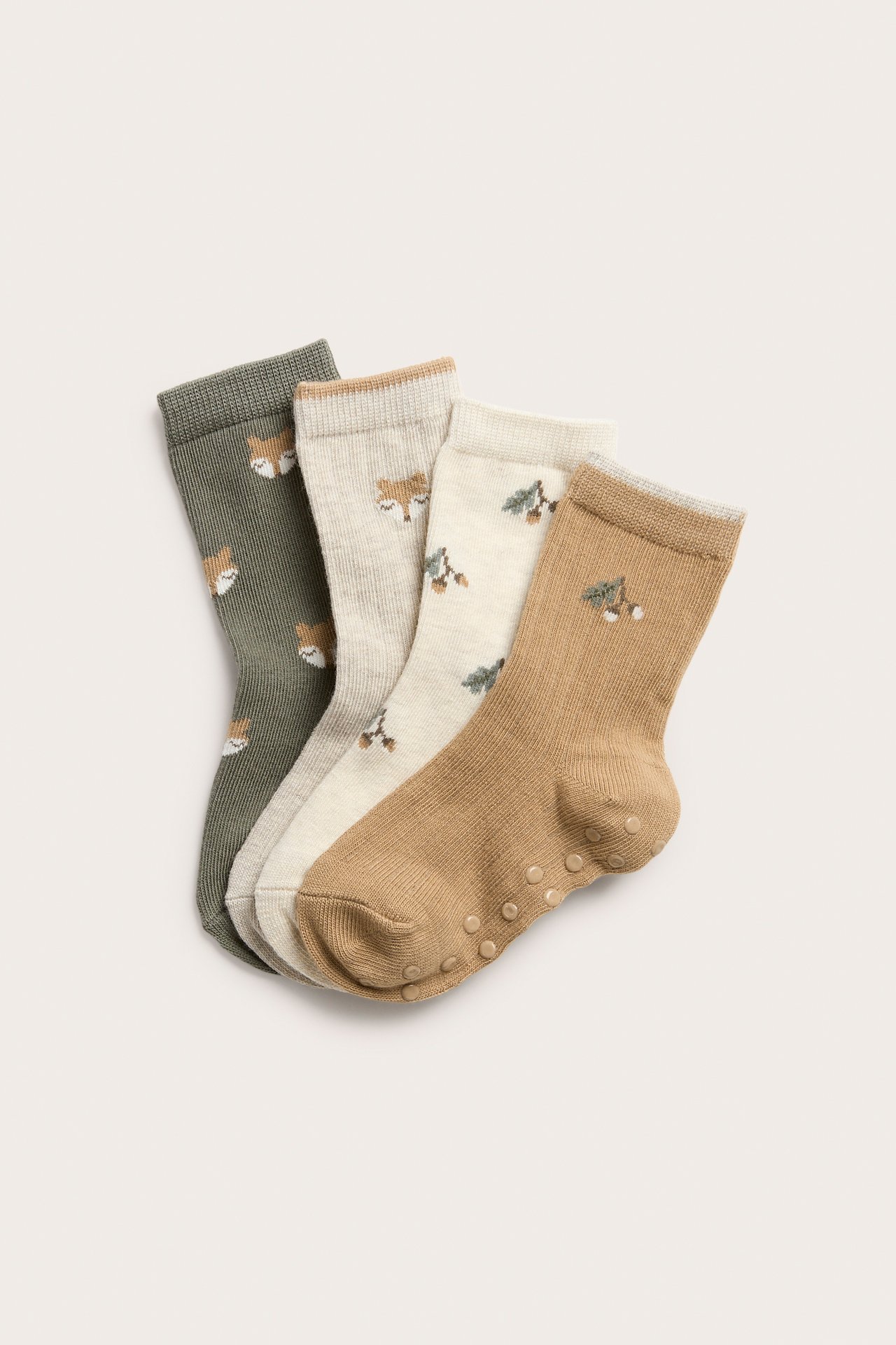 Close-up of four kid's patterned socks: dark green fox, light grey fox, off-white acorn, and light brown anti-slip.