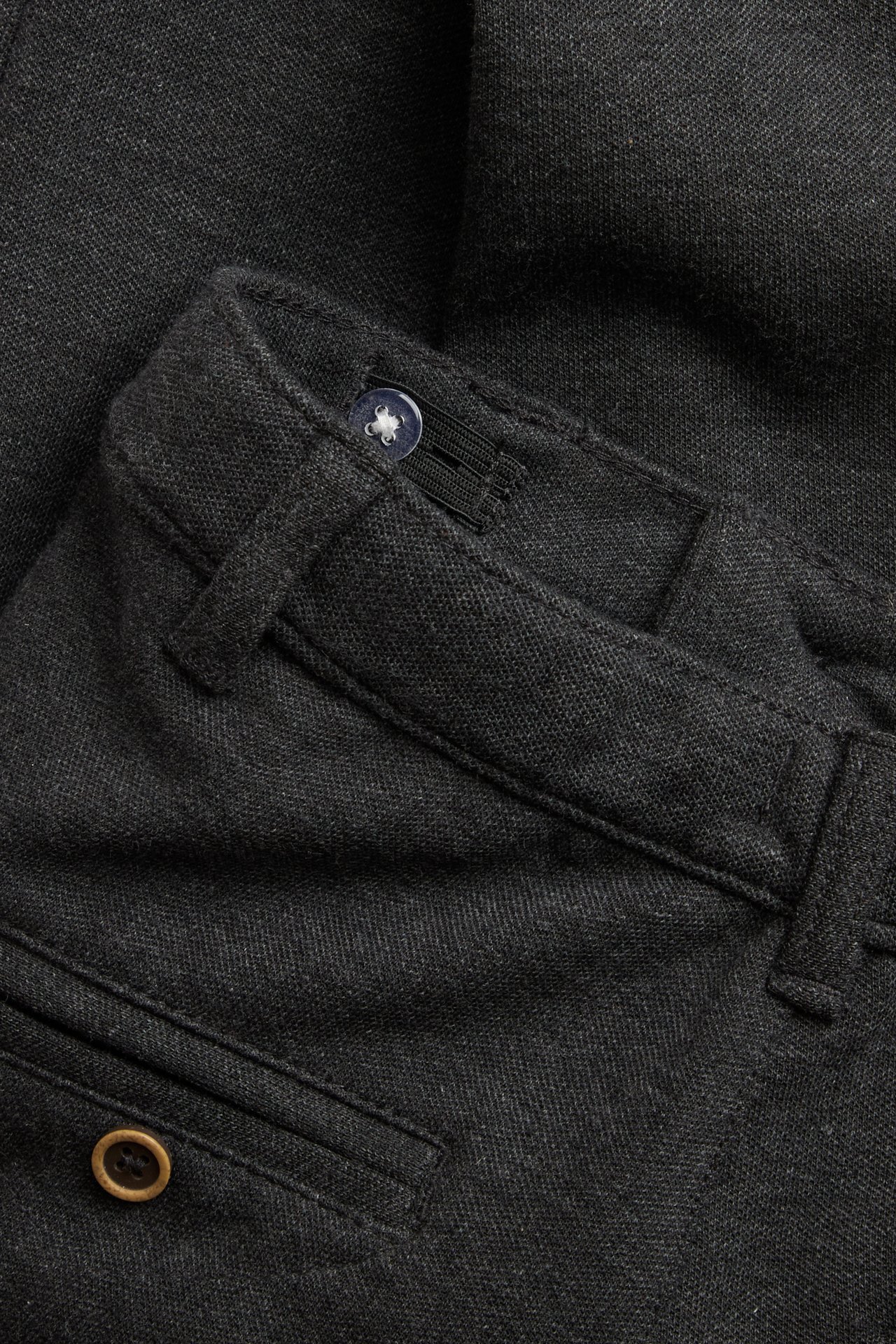 Nahaufnahme einer dunkelgrauen Hose mit verstellbarem Gummibund und Knopfdetail hinten.