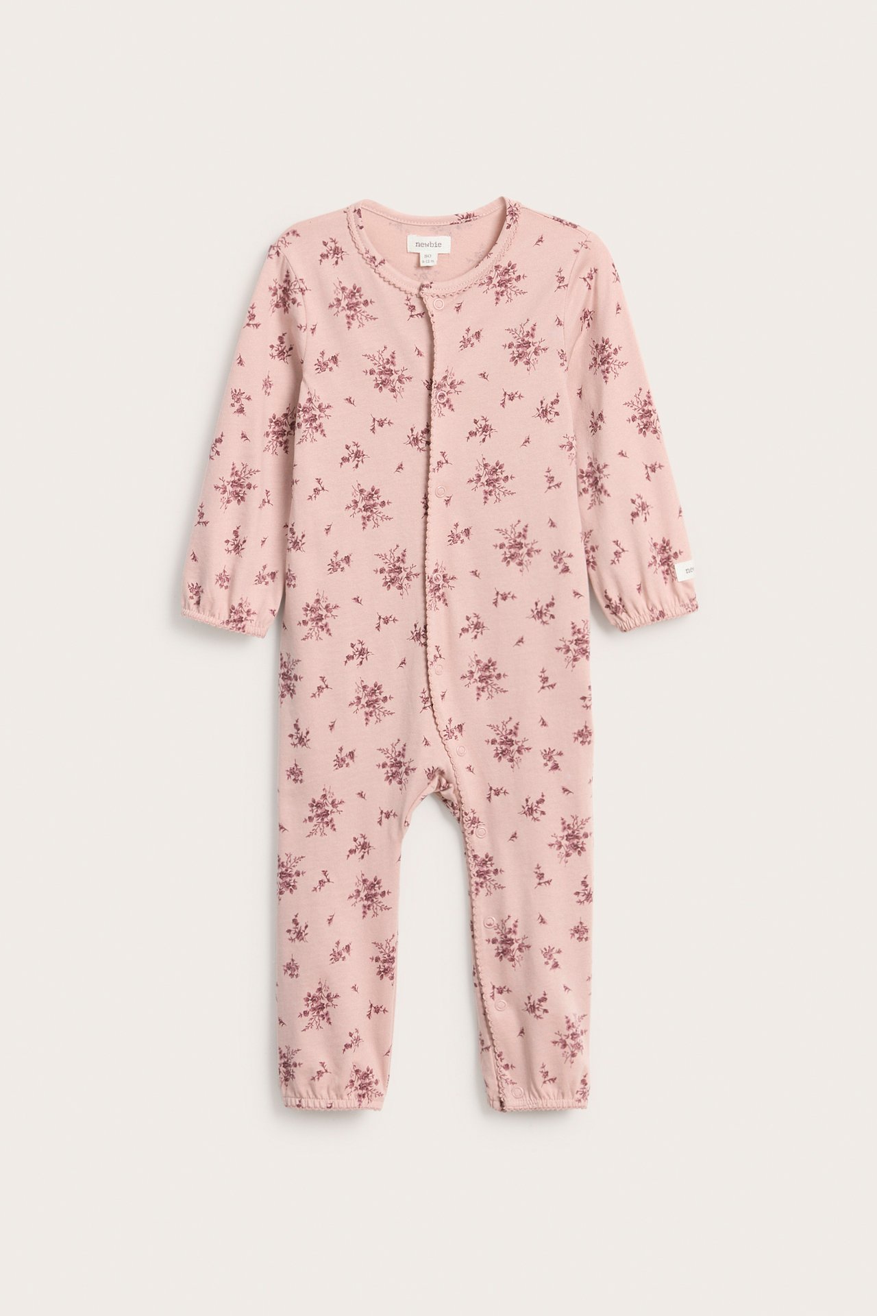Front view of a pink cotton baby pajama with a tone-on-tone floral pattern and front snap buttons.