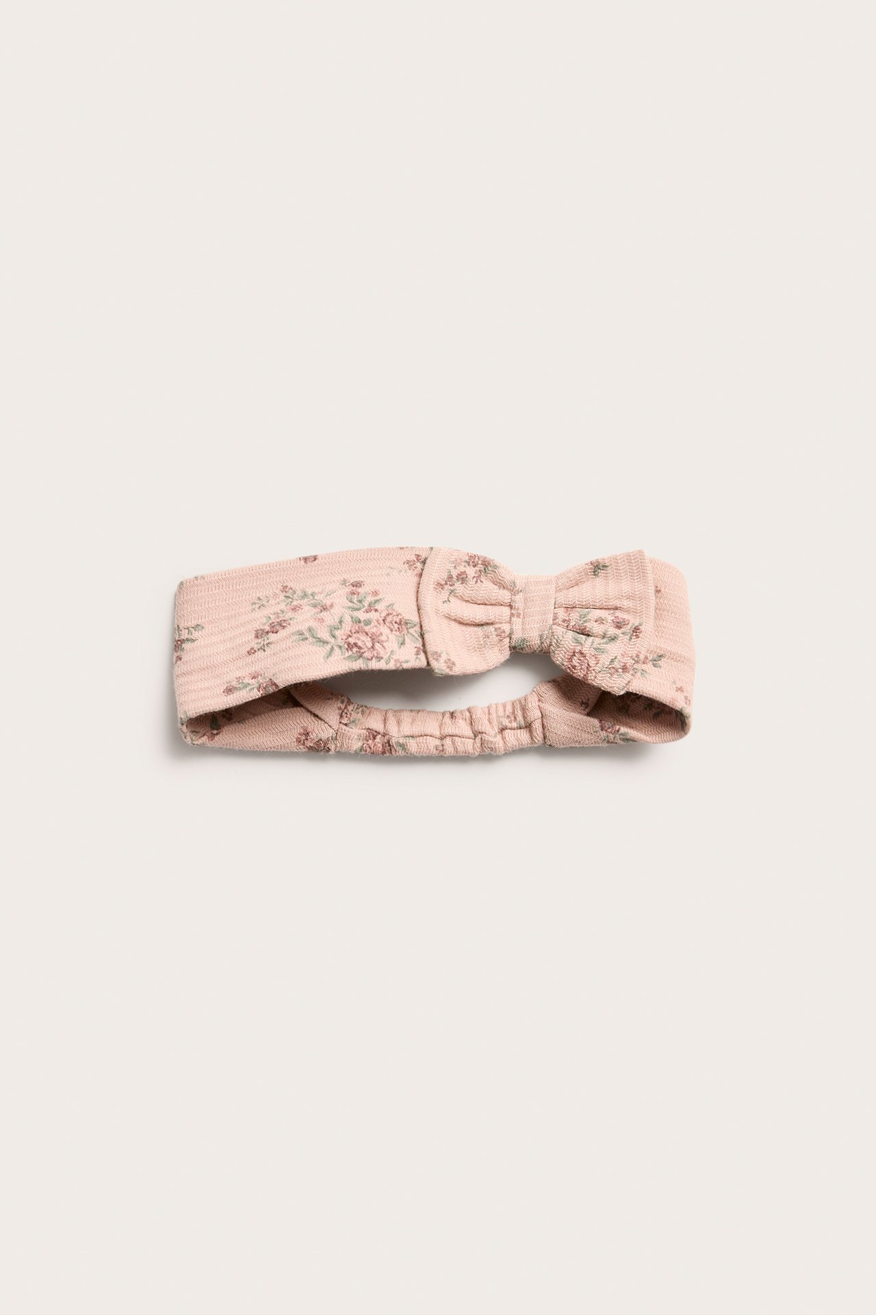 Close-up of a pink floral cotton jersey headband with a front bow and elastic back.