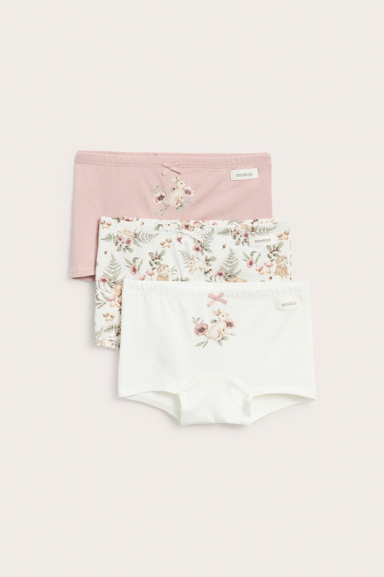 Vorderansicht von drei Kinder-Jersey-Boxershorts: cremeweiß mit Hasenprint, geblümt allover und hellrosa mit Hasenprint.
