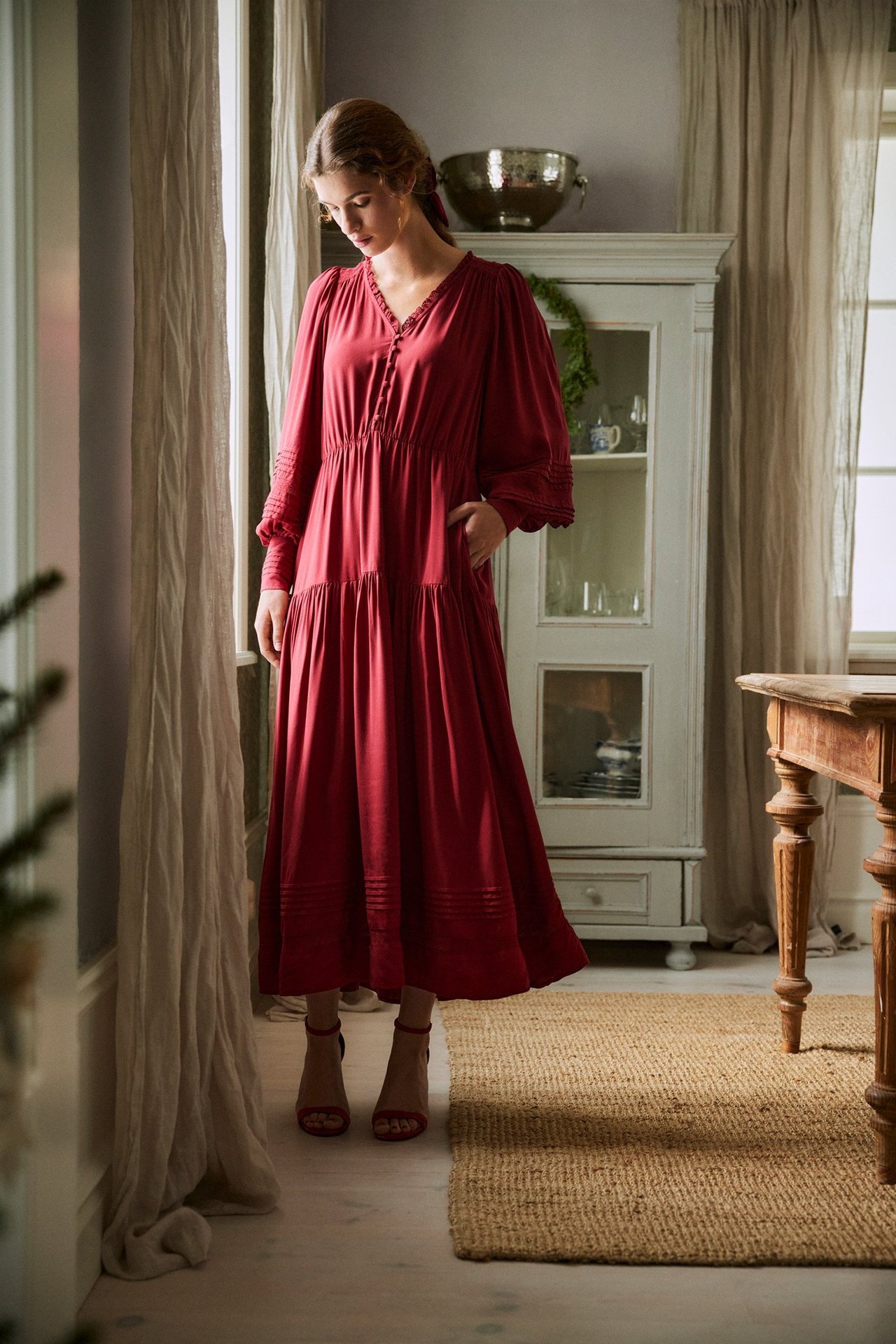 Front view of woman in red viscose dress with lace, pintucks, covered buttons, elastic waist, and red sandals.