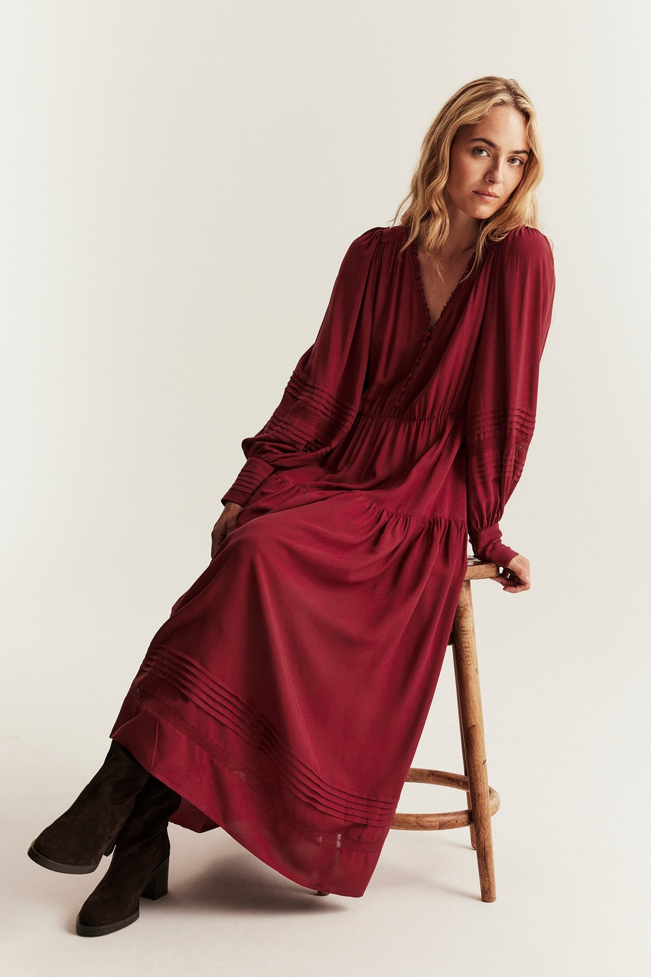 Red viscose dress with lace details, elastic waist, worn by woman seated on stool.