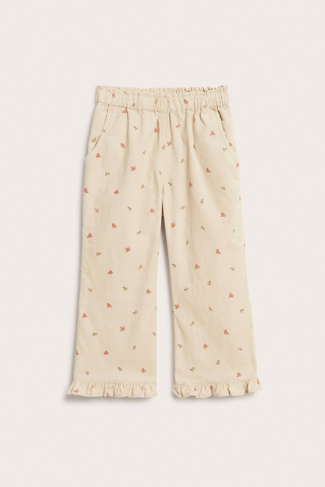 Vorderansicht: Beige Kinder-Cordhose mit Blumenmuster, Gummibund, Vordertaschen und Rüschensaum.