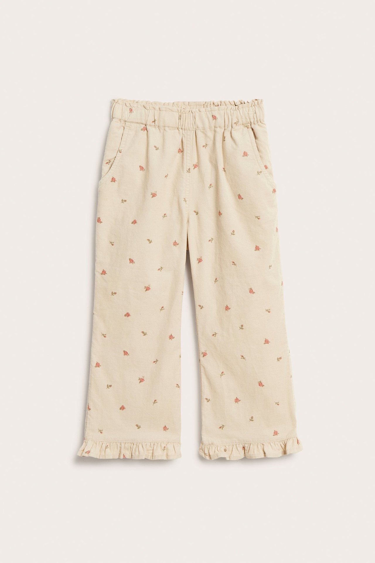 Vorderansicht: Beige Kinder-Cordhose mit Blumenmuster, Gummibund, Vordertaschen und Rüschensaum.