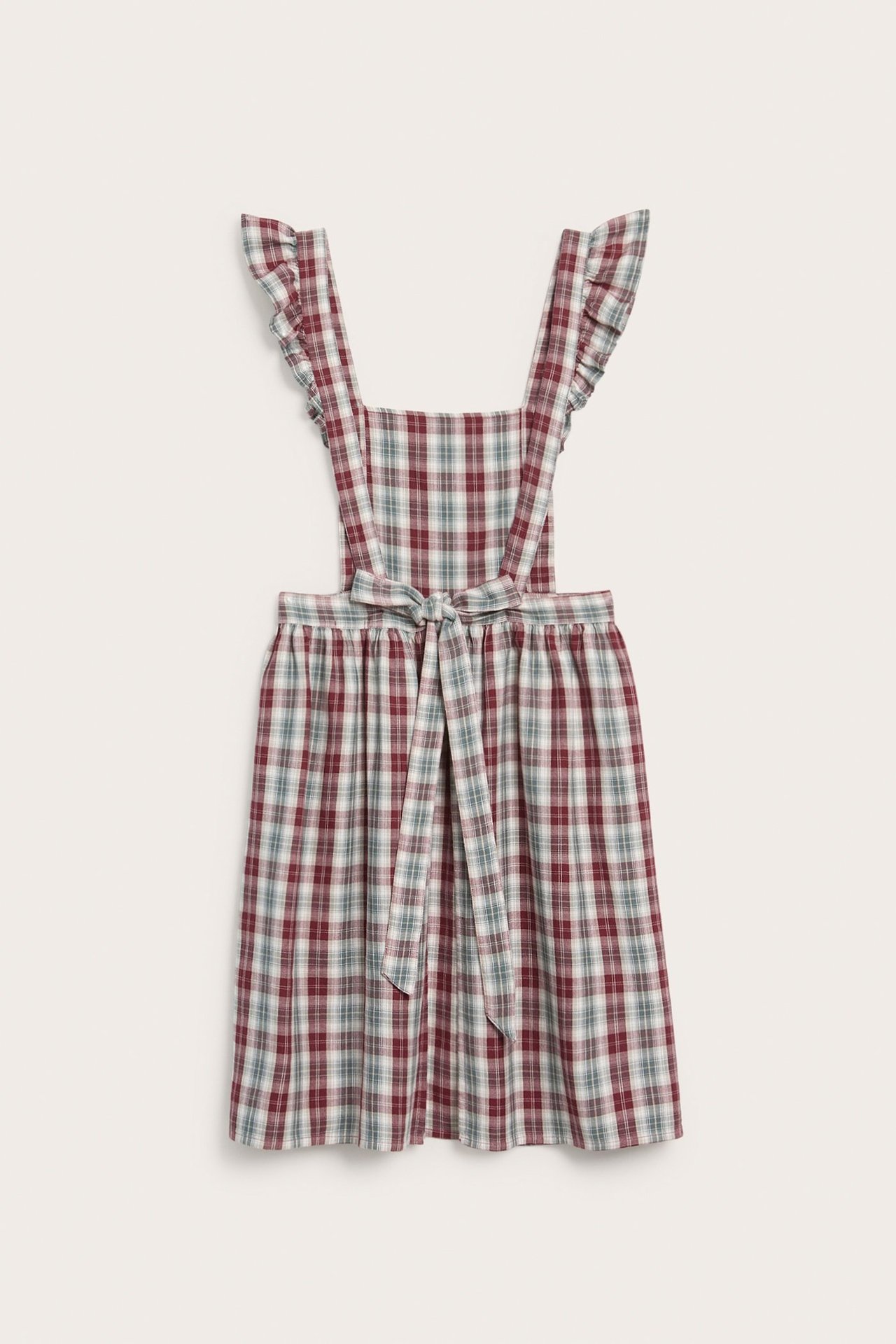 Front view of a woman's red, green, and white checked cotton apron dress with ruffled straps and tie-waist.
