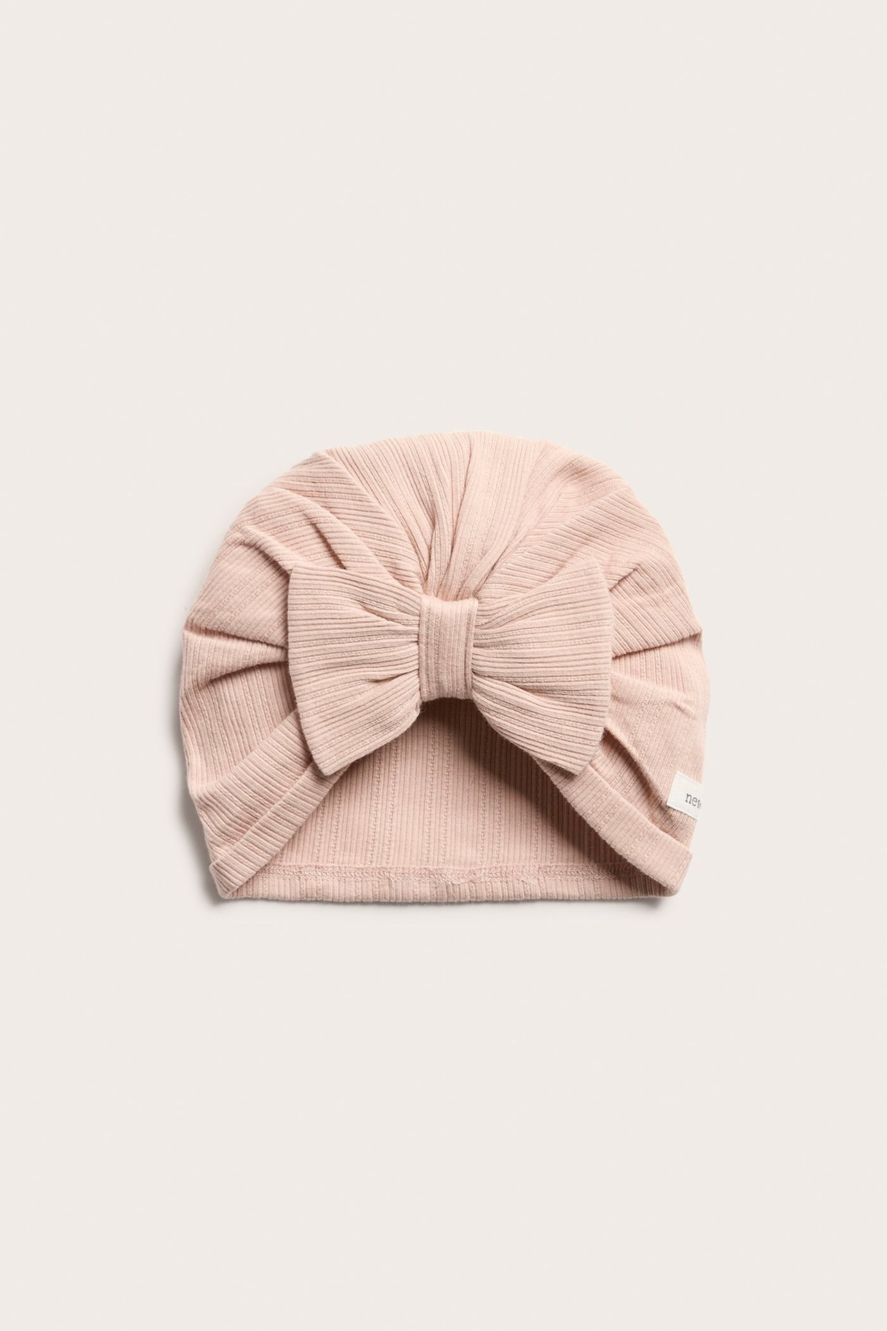 Vorderansicht einer rosa gerippten Baby-Turbanmütze mit großer Schleife.