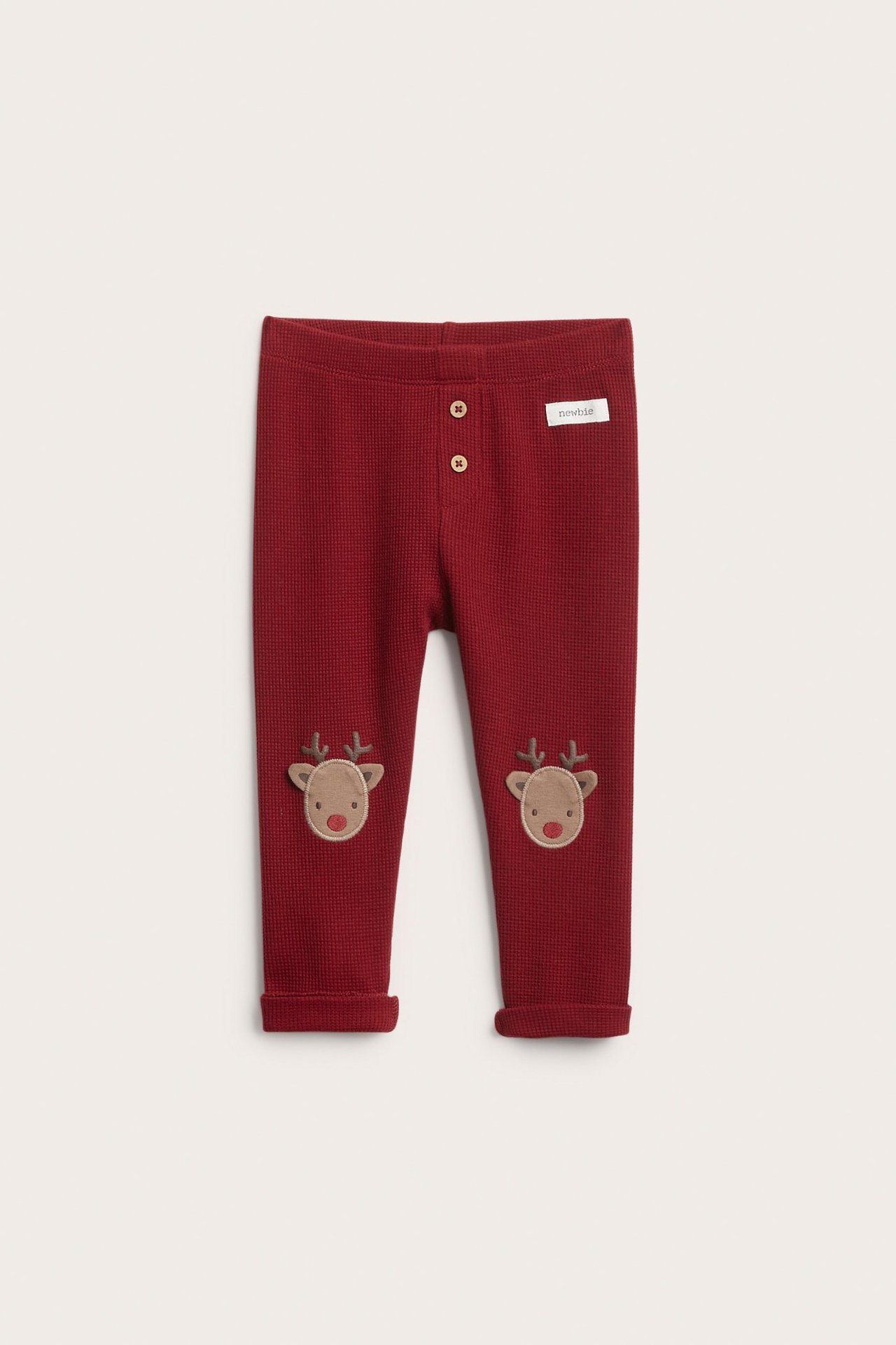Red knee-length leggings with waffle texture, decorative buttons, reindeer appliqué.