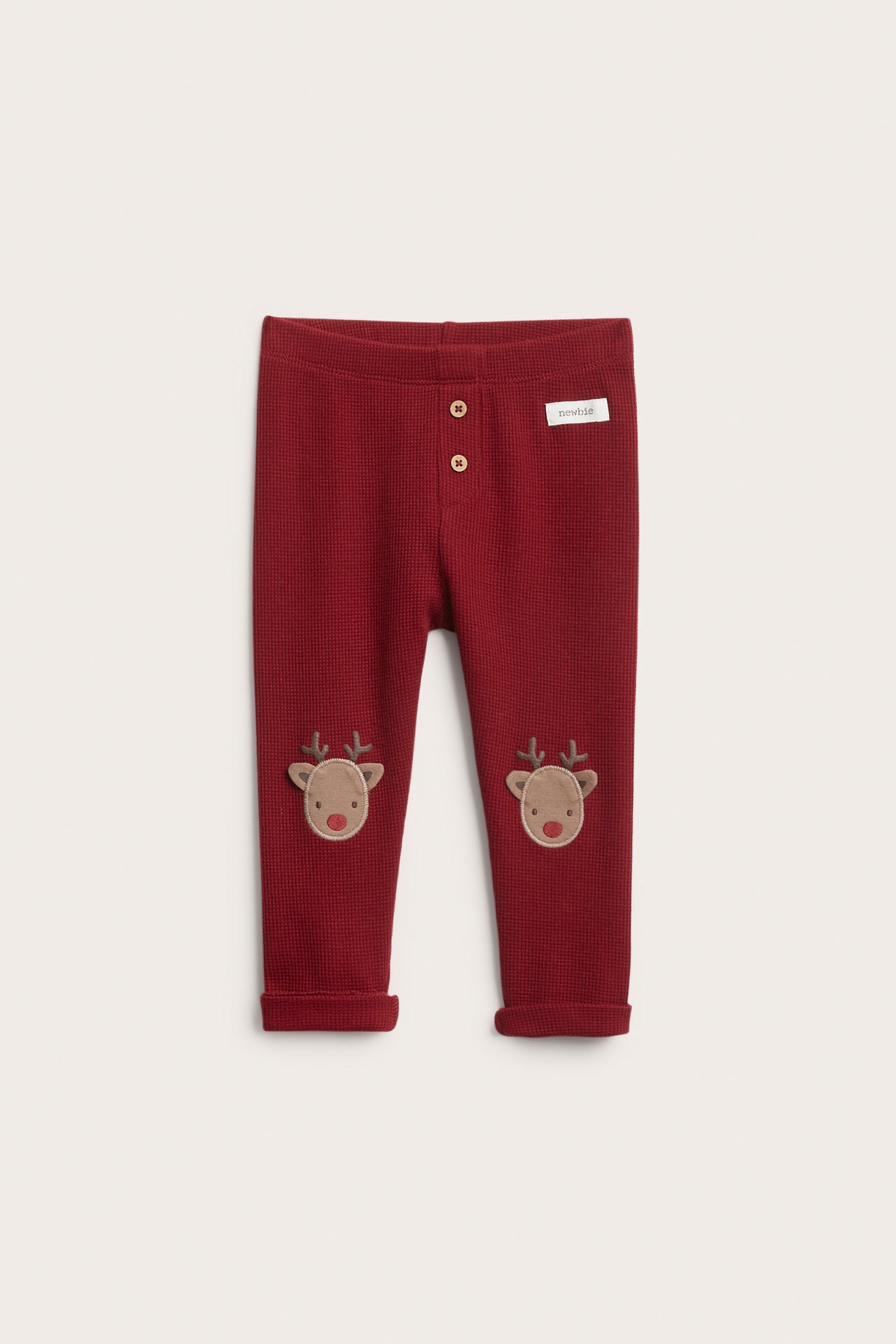 Vorderansicht: Rote Baby-Waffelstrick-Leggings mit Knöpfen und Rentier-Applikationen auf den Knien.